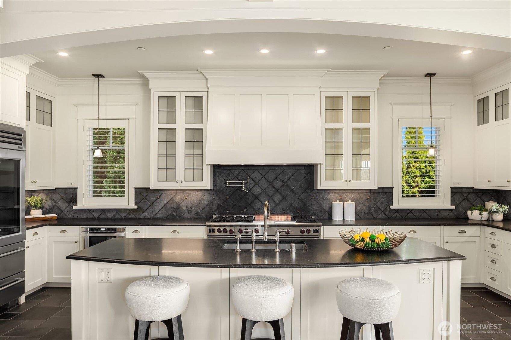 Everyone wants to gather here in this Epicurean's Dream kitchen that shines boldly with its massive island, custom leaded glass cabinetry and the mack daddy of Bosch stoves:  the 6 burner with double ovens + a griddle and grill.