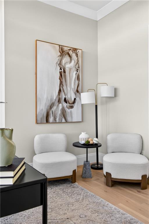 Living area with light wood-style flooring and crown molding