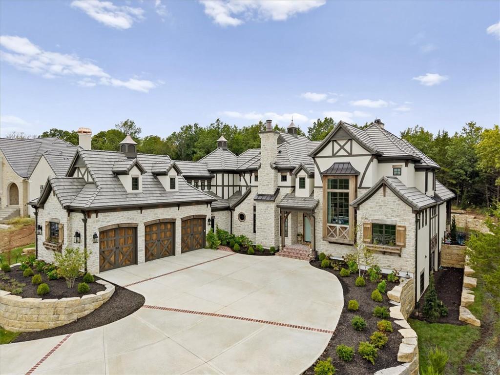 Double Eagle custom English storybook Tudor with Mission Hills style architecture and brand-new construction in Loch Lloyd!  A home where timeless architecture meets exceptional craftsmanship.  Seller has plans and lower-level finish designed and plumbed ready for the next buyer. 4th bedroom can easily be added in the upstairs with closet and bathroom already in place. So many exceptional upgrades include 8" white oak flooring, EV wired garage, custom handmade lighting from England, custom cast stone fireplace, upgraded hvac, reverse osmosis water system, specialty hardware, inset cabinets and more.  This home will captivate you with its dramatic vaulted ceilings that include handmade exposed wood beams and statement lighting along with the beautifully detailed millwork and custom cabinetry. Every space feels thoughtfully designed and is truly one of a kind. The heart of the home is an impressive chef’s kitchen featuring an oversized furniture-style island, Aga luxury range with three cooking compartments, expansive stone countertops and elegant brass accents. The adjoining living spaces are equally striking, highlighted by soaring ceilings, a beautifully detailed cast stone fireplace and walls of windows that fill the home with natural light.  The scullery behind the kitchen has natural light, milk glass pendants and a vintage looking refrigerator. Designed for effortless indoor-outdoor living, multiple French doors open to an expansive covered brick veranda with exposed beams, generous entertaining and dining areas, and peaceful views of the surrounding landscape.  The entire area above the garage is 90% finished for additional storage or add a closet for an additional bedroom. Sellers also purchased a portion of the lot next door for privacy. Contact me for a private showing!