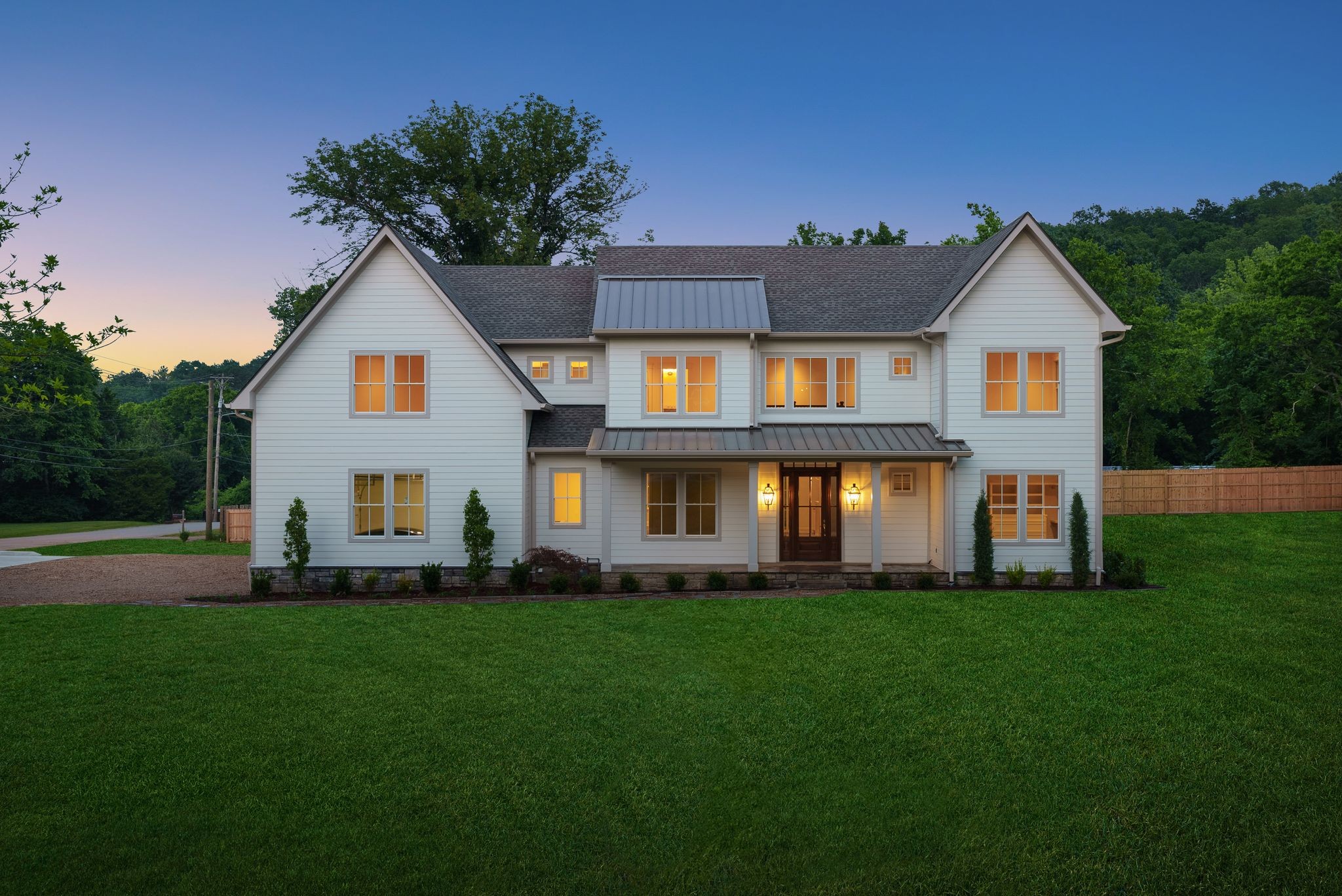 Located in Nashville’s highly sought-after West Meade, this stunning new construction home is built to the utmost standards using enhanced, specialized methods for superior durability, comfort, and high energy efficiency. Positioned on a sprawling 1-acre corner lot, this home offers nearly 4,900 sq. ft. of expertly designed living space with a 3-car garage, covered porches, and partial privacy fencing. The light-filled, open-concept floor plan features soaring ceilings, a two-story foyer, elegant formal and informal spaces, and a main-level layout ideal for modern living—complete with a luxurious primary suite and a private in-law or guest suite. The heart of the home boasts a family room with fireplace and custom built-ins and a chef-inspired kitchen with paneled appliances, premium stone, designer lighting and fixtures, commercial-grade gas range, and oversized walk-in pantry.
A seamless flow leads to a rear covered porch with Pennsylvania bluestone flooring, gas fireplace, and tongue-and-groove ceiling—perfect for outdoor entertaining. The primary suite offers its own porch entry, detailed ceiling, spa-like bath with heated floors, soaking tub, oversized tiled shower, and walk-in closet with custom millwork.   The second level includes 3 ensuite bedrooms, a study nook, secondary laundry, and spacious media/bonus room with wet bar and flex space. Designer-selected finishes throughout curated by Nashville’s Lizzie Pogue Interiors create a luxurious ambience. Constructed with focus on longevity, comfort, and performance, this home integrates advanced materials and systems rarely found in residential construction. Just minutes from top schools, shopping, parks, and more, this one-of-a-kind property offers luxury and resilience in one of Nashville’s most coveted neighborhoods.