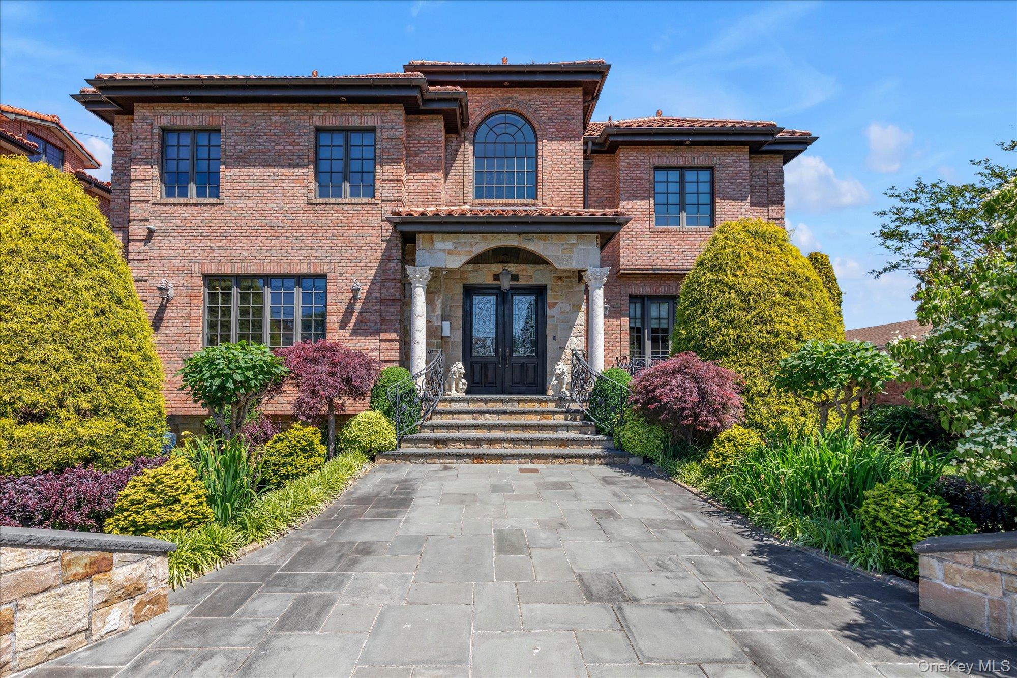 Located in the prestigious enclave of Malba, this extraordinary custom-built Mediterranean-style residence blends timeless elegance with exceptional craftsmanship.A grand entryway with soaring vaulted ceilings and a striking chandelier sets the tone for the home’s impressive design. The main level features a beautifully appointed sitting room and formal dining room with gleaming marble floors, along with an expansive open living area that seamlessly connects the gourmet kitchen and family room.The kitchen is designed for both everyday living and entertaining, offering a center island, maple wood cabinetry, granite countertops, and a convenient butler’s pantry for additional preparation and storage space. The adjoining family room is anchored by a gas fireplace and coffered ceiling, creating a warm and inviting gathering space. French doors open to a terrace overlooking the pool, spa, and outdoor kitchen—perfect for indoor-outdoor entertaining.The main level also includes a stylish powder room and laundry area. Upstairs, a grand wrought-iron staircase leads to a spacious landing and the luxurious primary suite, complete with a sitting area, French doors to a private balcony overlooking the backyard, a large walk-in closet, and a spa-like bath with double vanities, shower, and soaking tub. A spiral staircase from the primary suite leads to a spacious loft.Three additional generously sized bedrooms offer ample closet space and Brazilian cherry hardwood floors, including one with its own full en-suite bath. A full hall bath serves the remaining bedrooms.The full basement expands the home’s living space, while nine radiant heating zones and four central air-conditioning zones provide year-round comfort.With exceptional architectural detail, thoughtful design, and resort-style outdoor amenities, this remarkable residence offers a rare opportunity to experience luxury living in Malba.