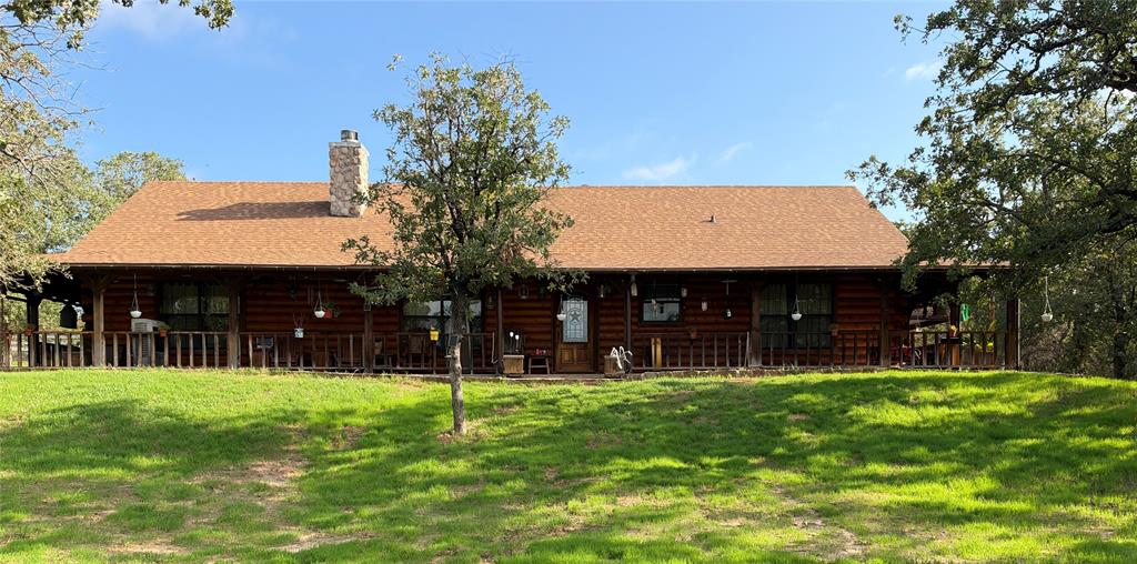 Custom Satterwhite Neches 8in D-log home on 10 acres in Springtown. Built 2003, 2,436 SF, 3BR-2BA, with a full wraparound covered porch and mature oaks. Interior is 90% tongue-and-groove wood with exposed wood beams, alderwood doors, and blue pine and aspen accents in two bedrooms and a bath. Vaulted great room features a Majestic wood-burning fireplace and Velux skylights. Kitchen and primary bath offer custom cabinetry, a reproduction antique-style electric range, and sawn, stained, and sealed concrete floors throughout. Primary suite includes a jetted triangle soaking tub, rain-head and body-jet shower, and dual walk-in closets. 10x24 sunroom addition with a 2-year-old mini-split, two Velux skylights, and tile floor. Wireless home automation and outdoor speakers. New Class 3 CertainTeed roof (May 2026), 3-zone radiant in-floor heat, and a 5-ton heat pump. 25x30 metal garage with two 10x10 roll-up doors, a 4.2kW 48V off-grid solar system (ground-mount sun-seeking and roof-mount panels, 300Ah battery backup), a 220V EV charger, and concrete driveways. Attached 2-car garage plus 2-stall carport, a 12x24 cedar tongue-and-groove workshop with AC and 220V electric, and two 12x12 finished storage rooms. Barn with four finished 10x10 stalls, a 10x10 tack room, water, and 200-amp electric; second drywalled outbuilding with wood floor; a small metal barn and metal shed, both with elec; additional carports throughout the barnyard. Manual backup generator with transfer switch and three separate 200-amp electric services to outbuildings. Private well (~300 ft, Trinity River Basin), aerobic septic with new 2026 controller and aerator, 4-zone WiFi irrigation, 50-gallon Polaris propane water heater, Starlink internet (primary and standby), property-wide security cameras, and gated electric entry. 5 acres cross-fenced with no-climb and 4-board white vinyl fencing plus barnyard pens, suited for horses or livestock. A rare blend of craftsmanship, systems, and acreage.