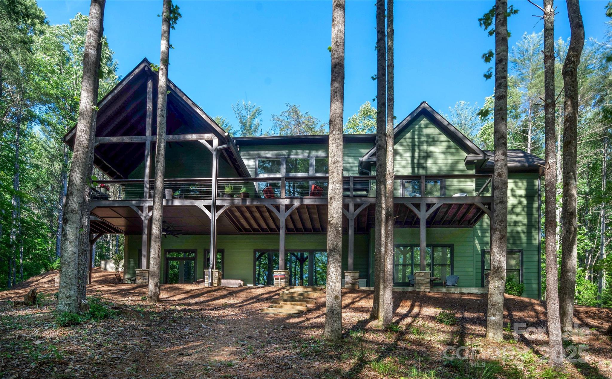 Take the road less traveled—this peaceful waterfront retreat in Dry Creek offers the perfect blend of spacious comfort and rustic Lake James charm. Nestled down a winding private drive, the home welcomes you with vaulted ceilings, a stone fireplace, and a well-equipped kitchen in a bright, open family room. Double doors open to a covered deck with serene views of a glistening cove, floating dock, and waterfront seating. The main level features a spacious office/flex room/, bedroom and a generous primary suite with deck access and water views. Downstairs offers nearly self-sufficient living with a second family room, kitchenette, and two additional bedrooms. With a gentle walk to the dock and complete privacy—no neighbors in sight—yet close to Morganton, this home truly makes all the difference.