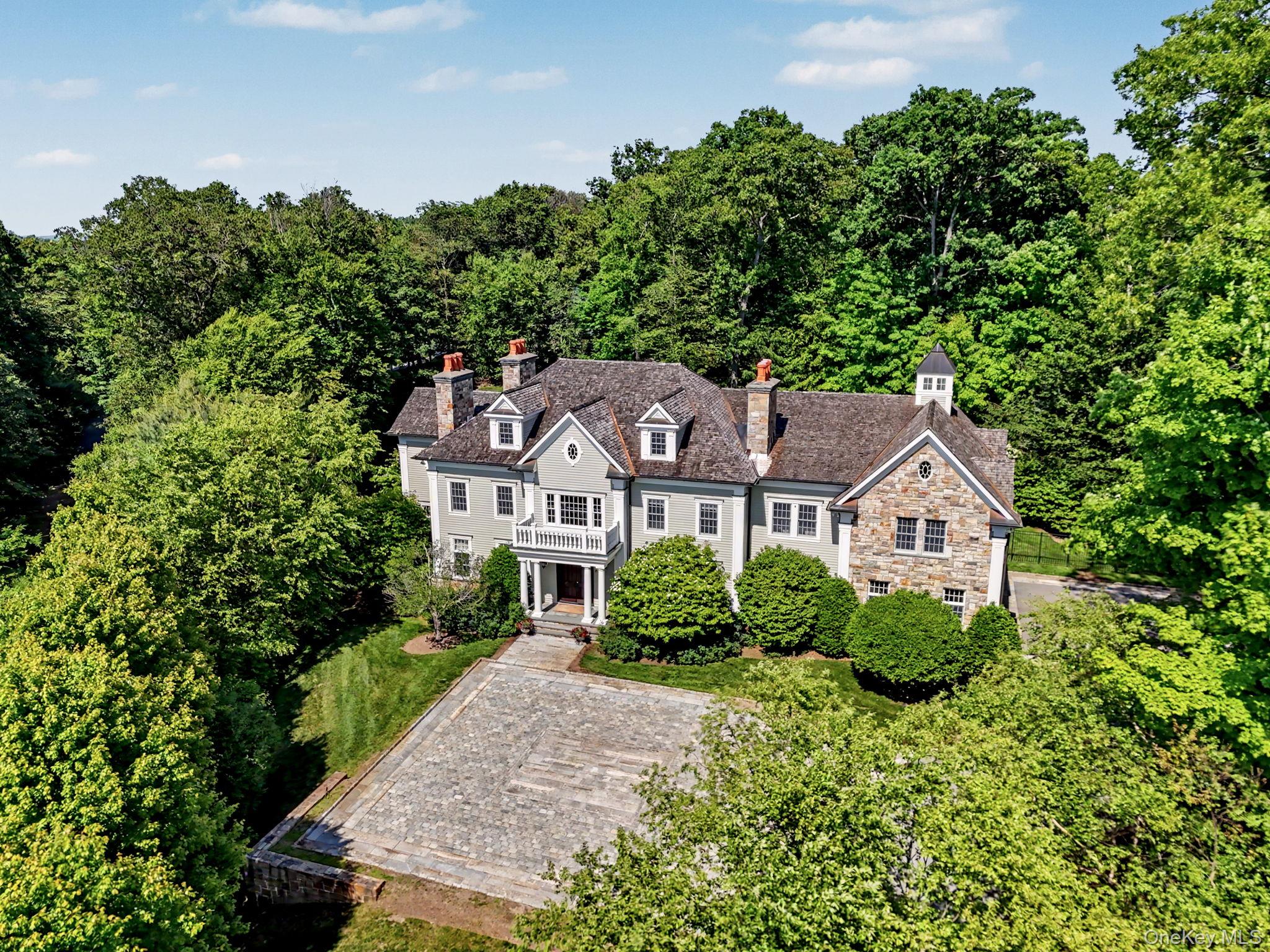 Privately set along a winding drive in the coveted Gifford Lake enclave of Armonk, this extraordinary estate offers the feeling of a year-round retreat. Homes of this caliber are defined by extraordinary millwork, full stone cladding, bespoke interior detailing, and museum-quality finishes, reflecting an uncompromising standard of craftsmanship rarely realized in today’s luxury landscape.While rich in architectural pedigree and old-world craftsmanship, the home’s thoughtfully curated color palette, refined designer lighting, and seamless integration of modern materials and fixtures create a sophisticated and current aesthetic. The result is a timeless yet fresh ambiance that feels elegant, vibrant, and thoughtfully modern in its presentation.The exceptional depth of materials and masterful execution throughout this Gifford Lake estate truly distinguish it from anything else on the market. Hand-finished Venetian plaster, intricate custom paneling and wainscoting, richly detailed coffered ceilings, curated designer lighting, premium marble and granite selections, and an extensive stone package that would be extraordinarily costly to replicate today establish a remarkable level of quality.A stone-pillared entry and antique granite courtyard introduce the home’s architectural pedigree. Inside, a dramatic double-height foyer with chevron hardwood flooring, elaborate millwork, coffered ceilings, and a sweeping staircase immediately showcase the craftsmanship carried throughout the residence. Five fireplaces with custom mantels and marble surrounds, crown molding across all levels, bespoke cabinetry, designer wallcoverings, premium marble and leathered granite surfaces, and integrated Sonos audio elevate every space.The chef’s kitchen features Wolf and Sub-Zero appliances, Arabescato marble, a substantial leathered granite island, custom wood cabinetry with glass display uppers, and a glass-wrapped breakfast area filled with natural light.The owner’s retreat serves as a private sanctuary with architectural ceiling detail, a bespoke dressing room with center island, radiant heated spa bath, and refined marble finishes.The fully finished walk-out garden level continues the home’s elevated design with a custom theater and built-in snack bar, brick fireplace lounge, bespoke bar, fitness studio, and resort-style entertaining spaces.Outdoors, full stone cladding, copper detailing, a heated saltwater pool and spa, custom outdoor kitchen, pergola, and professionally landscaped grounds complete this irreplaceable estate offering. Conveniently located near schools, shops, and acclaimed dining in the nearby towns of Armonk, Bedford, and Greenwich, and served by the award-winning Byram Hills School District.   Some Photos enhanced for seasonal representation.