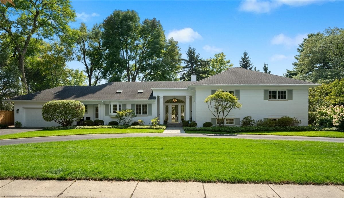 This timeless 4 bedroom 3.1 bathroom white brick split-level home sits on a beautifully landscaped 1/2-acre lot on a quiet, private street. A true Winnetka gem- this Hemphill home has 3,800 SF!  The property offers the rare convenience of both an attached garage and a circle driveway, with a welcoming bluestone walkway leading to the front door.  Inside, a bright foyer opens to sun-filled living spaces with southern exposure and sweeping views of the backyard. The living room, anchored by a gas fireplace and bay window, flows seamlessly into the dining room and family room, where sliders open to the patio for easy indoor-outdoor living. The updated kitchen is a standout, with vaulted ceilings, beams, skylights, white quartz countertops, new appliances, modern lighting, and fresh hardware, and connects to a mudroom with first-floor laundry.  The split-level layout checks every box: just eight steps up to three spacious bedrooms and two updated full baths, including a primary suite with a private balcony overlooking the backyard. Eight steps down leads to a bright ground level with a large recreation room, walk-out patio, a fourth bedroom, renovated full bath, and utility room.  Thoughtful updates include newer windows, dual 2023 HVAC systems, and a 2025 water heater. Additional features include a pull-down attic for abundant storage and an attached garage with a dedicated storage shed.  Outdoor living shines with multiple patios, mature trees, and expansive green space-a true half-acre retreat in the village. A sprinkler system keeps the grounds lush and green. The 136-foot-wide lot provides privacy and space rarely found at this price point, where most Winnetka lots are only 50 feet wide.  All of this in an unbeatable walk-to-everything location-just steps from neighborhood schools (K-8), as well as Skokie Playfield's tennis courts, baseball fields, hockey rink, and park amenities.  Plus taxes are under $18k.