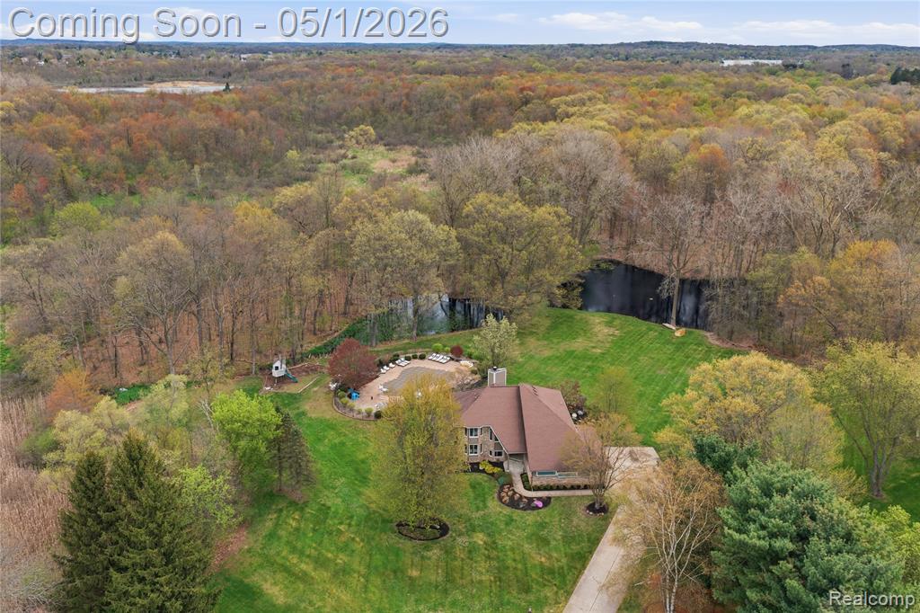 Imagine your morning coffee overlooking two private ponds with a fountain — just over 6.5 acres of wooded paradise at the end of a quiet cul-de-sac in White Lake Township. This is the up north lifestyle without the drive. An inground pool with new pump and filter. A built-in hot tub tucked into its own private space. A stone fire pit for summer nights that never end. A playset. Trails through the woods leading to an established blind. A backyard so big you won't want to come inside. Nearly 3,800 finished square feet with new flooring throughout. Floor-to-ceiling windows flood the great room with natural light alongside a gas fireplace built for cozy winter evenings. The open kitchen delivers double ovens, electric cooktop, and storage for days. Upstairs — a primary suite with skylight, walk-in closet, and an en suite with dual sinks, jetted tub, and separate shower. Two additional bedrooms and a full bath on the upper level. The finished lower level brings a second kitchen with bar area, a massive family room with its own gas fireplace, a fourth bedroom, and a full bath — set up for hosting, movie nights, or extended stays. Oversized 3-car attached garage. Huron Valley Schools. Minutes from downtown Milford, Highland, and every convenience you need. This is not just a home — it's a lifestyle. Welcome home.
