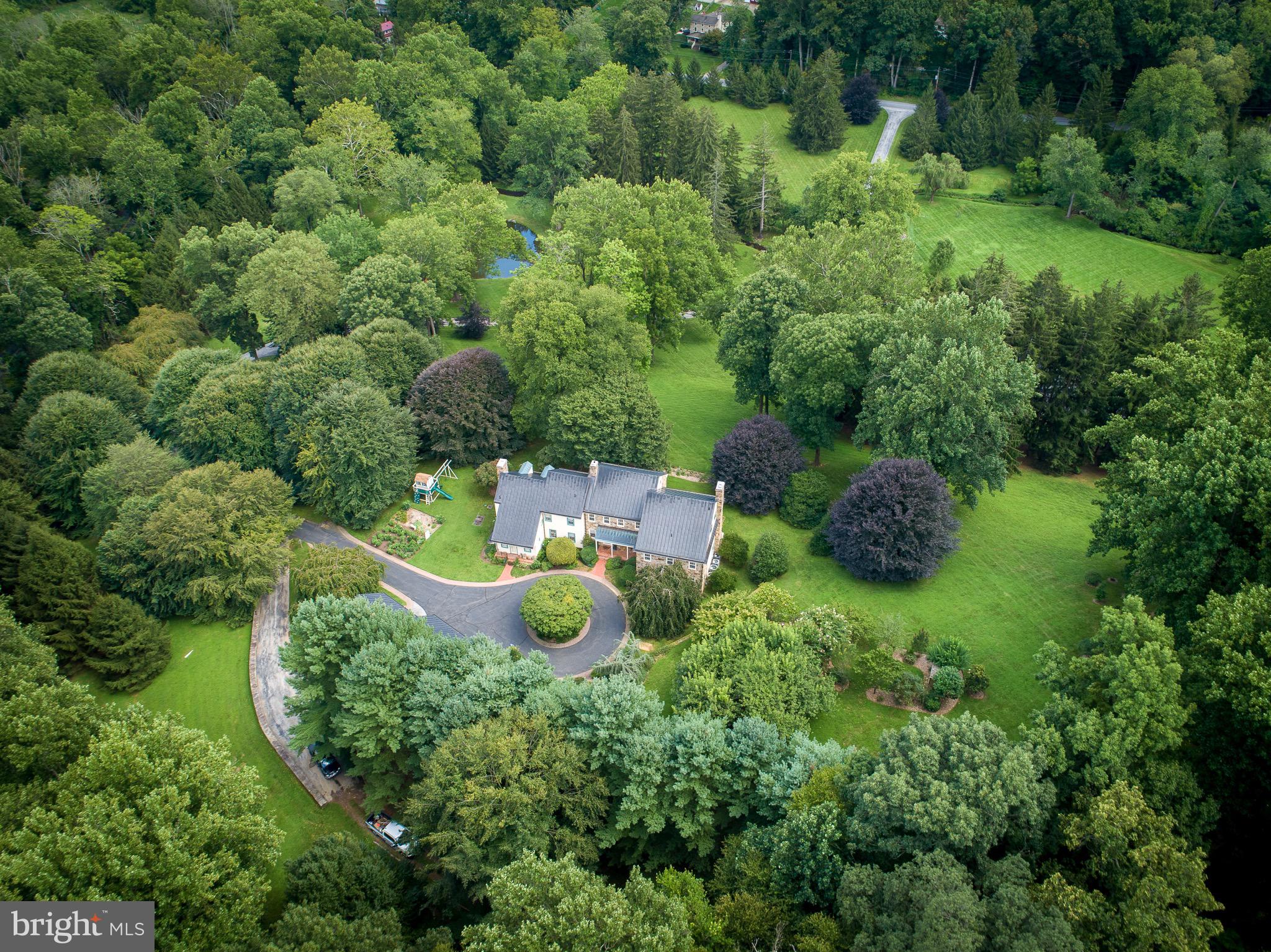 A truly rare offering in the heart of Birchrunville—this remarkable private estate combines timeless elegance, master craftsmanship, and serene natural beauty. Designed by acclaimed architect John Milner, this custom Chester County farmhouse is sited on over 30 acres of verdant grounds, offering the utmost privacy and refinement. Constructed to the highest standards, the home features fine stonework and distinctive touches such as intricate mahogany cornices and standing seam copper roofing. Inside, every detail has been thoughtfully curated: full plaster walls, bespoke millwork, and an exquisite blend of flooring materials including pegged walnut, 100-year-old long leaf yellow pine, herringbone brick, and imported tile. Every room was carefully designed to enjoy the southern exposure and idyllic views overlooking the Birchrun stream, a tranquil pond, open meadow, and partial woods with a variety of nature and landscape. The residence offers 4 Bedrooms, all with en suite baths. The elegant primary suite features a separate dressing room and private access to an upstairs bonus room.  Five fireplaces enhance the home’s living areas—including the living room, dining room, family room, primary suite, and guest suite. The mudroom offers a convenient wash basin for boots (or dogs!). A detached, four-car garage adds convenience and utility.Beyond the main residence, the estate features a fully restored 18th-century bank barn with an additional four-car garage wing—perfect for a car collection, event space, or studio.This property is enrolled in Act 319 for favorable tax treatment, without any deed restrictions.A rare masterpiece blending together quality, privacy, and possibility - it is ideal for the discerning buyer seeking timeless beauty in a coveted  Birchrunville setting.