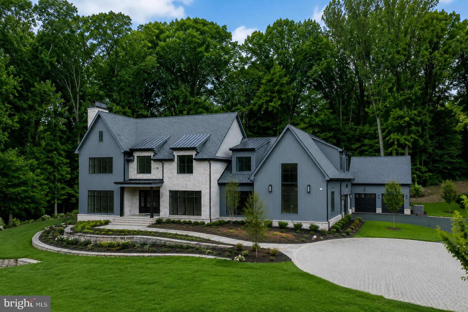 Quiet luxury has a new address in Great Falls. At 796 Falls Farm Court, Brush Arbor Homes has composed something rare - a New American Farmhouse of exceptional confidence and presence, sited up on 1.8 private acres with the kind of intentionality that finds its place in the landscape rather than imposed upon it.The façade announces its intention immediately: a refined palette of antiqued brick and board-and-batten siding in deep slate grey, anchored by a charcoal standing-seam roof and oversized black-framed windows that draw the eye and invite the light. Tiered stone retaining walls, manicured boxwood plantings, and a sweeping drive compose an arrival that is understated and impeccable. 11,800+- square feet of thoughtfully designed and light-filled interior space unfolds across three levels with 6 bedrooms, 8 full and 2 half bathrooms and optional elevator — formal entertaining spaces, intimate family quarters, and serene bedroom retreats — creating a warmth and livability that genuinely defies its scale. Wide-plank European white oak floors, soaring ceilings, and walls of glass anchor every room and announce the home's devotion to detail from the very first step inside.The rear of the home is nothing short of a private resort. A sparkling pool and separate raised stone-bordered spa anchor a generous bluestone patio, while an expansive covered outdoor living pavilion framed in the home's signature board-and-batten and finished with a full outdoor kitchen extends the interior's warmth and sophistication into the open air. A second-level balcony with black metal railings overlooks the entire scene. The surrounding lawn stretches generously in every direction, lush and level, offering abundant space for recreation, entertaining, or simply breathing room.This home's magic is found in the minutiae-in the deliberate choices that distinguish the exceptional from the merely impressive. Bespoke millwork and wainscoting, designer fixtures, and furniture-grade cabinetry and built-ins reveal a level of craftsmanship that must be experienced firsthand. Each room carries its own character while flowing effortlessly into the next, a testament to architecture that is as intelligent as it is beautiful.796 Falls Farm Court is a showcase of the best of everything the market has come to expect from Brush Arbor Homes. The discerning buyer will simply need to see it for themselves. Schedule a tour, and discover that true luxury is not simply seen, but deeply felt.