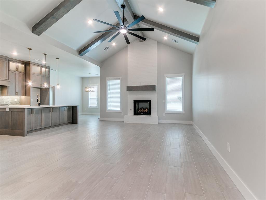 Welcome to this stunning new construction home in South Norman, perfectly positioned near OU and nestled beside a peaceful neighborhood pond stocked with fish. This thoughtfully designed 4-bedroom, 2 full bath, 1 half bath residence blends modern luxury with timeless finishes and an ideal, functional layout. The exterior makes a striking first impression with white painted brick, cedar beam accents, and a bold iron front door equipped with an electronic lock. Inside, soaring cathedral ceilings with stained wood beams create a grand yet inviting atmosphere, anchored by a dramatic floor-to-ceiling fireplace with a beautifully stained wood mantel. The kitchen is a true showpiece, featuring highly desired lower drawer cabinetry with custom hardware, quartz countertops, gold accents, a gas cooktop with pot filler, apron-front sink, and designer pendant lighting—offering both elegance and everyday functionality. Wood-look tile flows seamlessly through all high-traffic areas, combining durability with elevated design. Thoughtful details continue throughout the home, including a mud bench with hooks conveniently located off the garage entry, perfect for daily organization. The flexible front bedroom serves beautifully as a private office or guest space. The primary suite offers a true retreat with a tray ceiling and a spa-inspired bathroom featuring double door entry, elegant shiplap accents surrounding the tub, and a glass-less walk-in shower. The oversized walk-in closet is a standout, complete with floor-to-ceiling storage, a built-in dresser, and direct access to the laundry room for ultimate convenience. Two additional guest bedrooms are thoughtfully connected by a shared bathroom, creating a functional and comfortable layout for family or visitors.  With its prime South Norman location, upscale finishes, and serene pond-side setting, this home delivers a rare combination of craftsmanship, comfort, and convenience just minutes from campus, shopping, and dining.