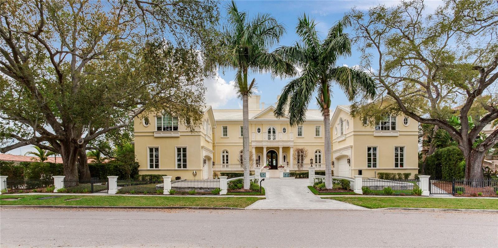 Experience the height of Livable Luxury in this extraordinary estate designed by Thomas Everett Lamb and built by Windstar Homes, an award-winning custom builder with over 100 industry accolades for craftsmanship and architectural excellence. Positioned on the open bay along Davis Islands, this one-of-a-kind residence blends timeless design with resort-style living. Created for grand-scale entertaining and refined everyday living, the home captures sweeping bay views, expansive terraces, and meticulously curated interiors. A stately arrival welcomes with parking for 9 vehicles and a 4-car garage, framed by hand-cast cement trim, shell detailing, and custom copper lanterns. Twin fountains accent the circular glass-paneled French doors, opening to a breathtaking foyer highlighted by a sweeping spiral staircase, intricate filigree ironwork, layered crown and dentil moldings, and a dramatic domed ceiling. The Grand Salon and formal dining spaces, including a dining alcove flanked by dual wine rooms with beveled glass, feature hardwood floors, hand-carved limestone fireplaces, and floor-to-ceiling arched windows. Walls of glass frame the west-facing veranda, gazebo, pool, fire pit, party dock, pickleball court, and unobstructed open bay. Exceptional craftsmanship is evident throughout, with concealed air-conditioning vents seamlessly integrated within the crown molding, deep windowsills, and extensive custom millwork. The chef’s kitchen centers around a massive island with beveled stone countertops and dual crystal chandeliers, complemented by Sub-Zero refrigeration, double dishwashers, and a Wolf range with griddle. A fully equipped scullery kitchen offers commercial refrigeration, double ovens, and additional prep space, ideal for catered events. A butler’s pantry, mudroom, and secondary laundry enhance daily functionality. Seamless indoor-outdoor living unfolds as the kitchen and great room open to a covered terrace featuring a pizza oven, warming drawer, beverage refrigerator, ice maker, sink, gas grill, and generous seating and dining areas overlooking the pool and bay. The first level also includes a bayfront office with custom cabinetry and fireplace, a game room with bar and adjacent theater, as well as a gym, craft, and multipurpose spaces. A private guest suite with rotunda seating, kitchenette, and elaborate bath completes the main floor. Upstairs, the primary suite is a private sanctuary occupying nearly one-third of the level. Entered through a grand vestibule, it features a bayfront sitting room with terrace access, limestone fireplace, dual custom walk-in closets with crystal chandeliers, and a spa-inspired bath with fireplace, steam shower, and marble finishes. Additional bedroom suites offer ensuite baths, custom cabinetry, and tranquil water or garden views, with many opening to private terraces. A separate guest or nanny suite, accessible via stairs and a hidden passage, includes a full kitchen, living area, bedroom, walk-in closet, laundry, and full bath. Outdoor living rivals a private resort, with a gazebo featuring marble bar seating for ten, a resort-style pool, fire pit, multiple terraces, pool baths, and a fully equipped kitchen. A crow’s nest terrace captures west-facing sunsets over the bay. With elevator access, 3 staircases, integrated technology, whole-home audio, and thoughtfully designed flow, this Davis Islands estate delivers architectural grandeur, modern luxury, and an unparalleled waterfront lifestyle.