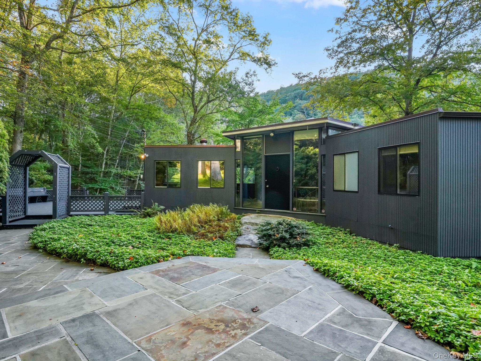 Welcome to West-Running Brook. There are idyllic settings and then there are properties like this. Only 1 hour from Manhattan, you’ll find breathtaking views and unmatched tranquility. From the moment you arrive, you will be captivated by the sweeping panoramic views, professionally designed gardens, rocky outcroppings, and a private pond with perimeter walking trail. All of this seamlessly blending into the untouched natural beauty of the abutting preserve. Set at the edge of the Ward Pound Ridge Reservation, this remarkable home sits within a landscape so naturally integrated, it's difficult to tell where the property ends and the preserve begins. With uninterrupted views of the Reservation’s mountainous terrain, the setting is nothing short of cinematic. The 4,315-acre Ward Pound Ridge Reservation is Westchester’s largest park and a protected nature preserve, offering miles of wooded trails along with year-round activities such as hiking, fishing, camping, and cross-country skiing. What’s more, you can access the Blue Trail directly from this property. The landscape was thoughtfully designed by Barbara Paca, an acclaimed landscape architect and preservationist known for creating timeless, low-maintenance landscapes that blend art, ecology, and historical context. Here, she created a garden that requires little upkeep while delivering beauty throughout the year. The home itself was designed by Edward Schildbach, a noted mid-century architect with a lasting legacy throughout the area. This home reflects his signature use of natural materials, clean lines, and large-scale windows that blur the line between indoor living and the surrounding landscape. His work continues to shape the architectural identity of the region — even a street in neighboring Bedford carries his name. Featuring two bedrooms on the main floor and a third on the lower level, this home presents exciting opportunities for customization. This one is for those seeking an extraordinary property rarely seen on market. Low taxes. Award-winning schools. A must see!