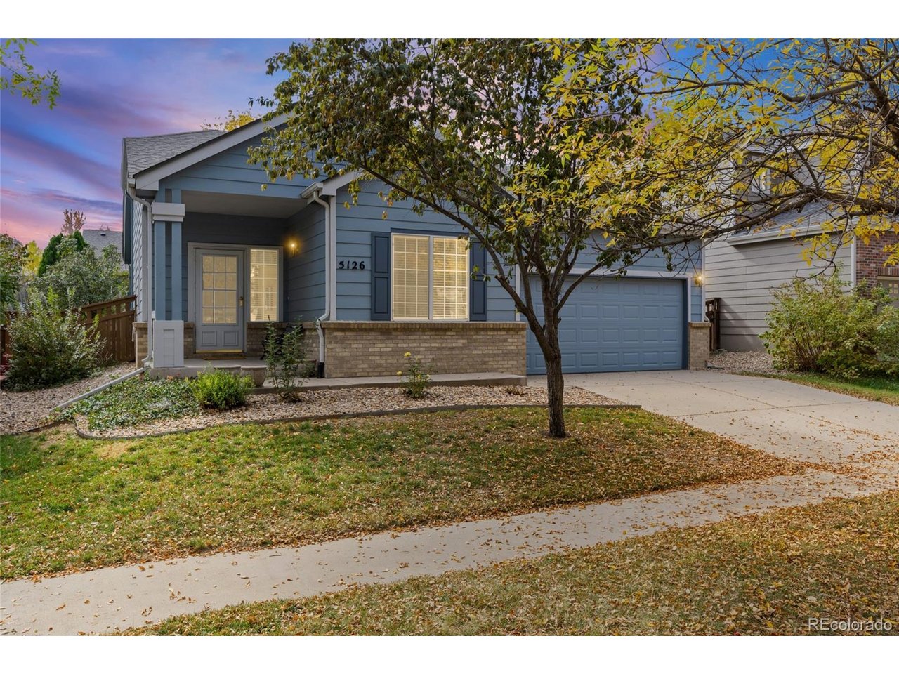 Welcome to this inviting Brighton home featuring 3 bedrooms, 2 bathrooms, and 1,325 square feet of thoughtfully designed living space. The vaulted living room creates an open, airy feel, with large windows filling the space with natural light. The kitchen offers ample counter space, generous cabinetry, and convenient backyard access through a sliding glass door. Privately situated just beyond the kitchen, the spacious primary suite features a large window overlooking the backyard, a walk-in closet, and an en-suite bathroom with a tub/shower combination and a large vanity. A second full bathroom provides additional counter space and storage, while the dedicated laundry room offers plenty of room for everyday convenience. Step out back to enjoy the expansive poured-concrete patio with Sunsetter awning, mature shade trees, and lush, fenced backyard. A two-car garage adds extra convenience and storage. With easy access to I-76 for a convenient commute to Denver, plus nearby shopping, dining, and major roadways, this Brighton home combines a functional layout, comfortable living spaces, and a great outdoor setting. A wonderful opportunity to settle in and make it your own!