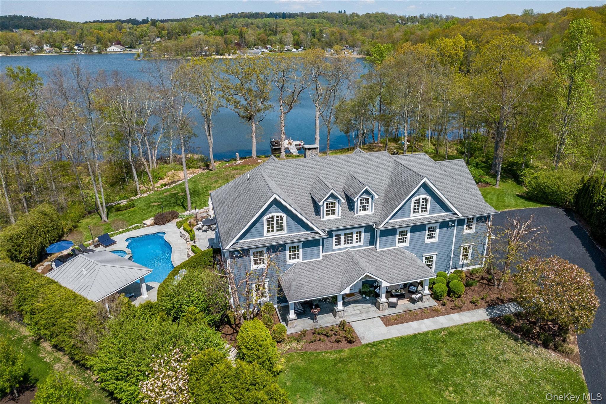 Blue Heron at Peach Lake is a rare lakefront retreat tucked away on 3.46 private acres at the end of a quiet cul-de-sac in North Salem. This exceptional 5-bedroom, 4.5-bath estate offers direct waterfront living with a private dock, sandy beach, and sweeping views of Peach Lake.Designed for both entertaining and everyday luxury, the outdoor setting features an in-ground pool with integrated spa, poolside cabana with bathroom, expansive stone patios, perennial gardens, and mature specimen trees. Gas-plumbed real-flame lanterns and a built-in firepit create a resort-like atmosphere across multiple outdoor gathering spaces.Inside, timeless craftsmanship is showcased through extensive custom millwork, generous living spaces, and a stunning oversized eat-in kitchen that anchors the home’s main level. Radiant heated floors run throughout the home and garage, adding year-round comfort and luxury. The expansive lower level offers a large gym, bonus/recreation room, and abundant storage, providing exceptional flexibility for lifestyle and entertaining needs.Set in the heart of Westchester’s celebrated horse country, the property combines privacy and convenience — approximately one hour from NYC, one hour to the Catskills, and just minutes to Metro-North.A truly rare offering combining acreage, privacy, refined craftsmanship, and authentic lakefront living.