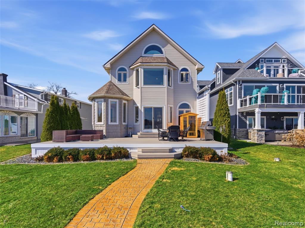 Lakefront Living on All-Sports Lake Fenton. Experience the beauty of lakefront living in this spacious 5-bedroom home on all-sports Lake Fenton in Fenton. Offering 3,495 square feet of living space and 43 feet of prime lake frontage, this property delivers stunning water views, generous living areas, and the perfect setting for entertaining or everyday comfort. The open-concept main level centers around a beautifully designed kitchen featuring abundant cabinetry, granite countertops, a large center island, stainless steel appliances, a built-in stovetop and oven, and a stylish gray tile backsplash. A raised bar provides additional seating for guests, while the nearby dining area includes a convenient wet bar—perfect for hosting gatherings. The kitchen flows seamlessly into the dining and living spaces, where an abundance of windows fills the home with natural light and showcases the lake views. Upstairs, you’ll find spacious bedrooms and the convenience of a second-floor laundry room. The primary suite offers vaulted ceilings, a large bay window overlooking the water, and a private bath complete with a double vanity and step-in glass shower. An additional finished level above provides flexible space ideal for a den, home office, studio, or private retreat. Fresh carpet and hardwood flooring run throughout the home, adding warmth and style. Outdoor living is just as impressive, featuring a beautiful deck off the back of the home—perfect for relaxing or entertaining while enjoying the lake scenery. A paved walkway leads directly to the water, where you can take full advantage of your 43 feet of lake frontage. Additional highlights include a detached 2-car garage with attic storage above, plus an unfinished basement offering 1,422 square feet of additional storage space. Whether you're looking for year-round lake living or the perfect place to entertain and unwind, this Lake Fenton home offers space, views, and an unbeatable waterfront lifestyle.