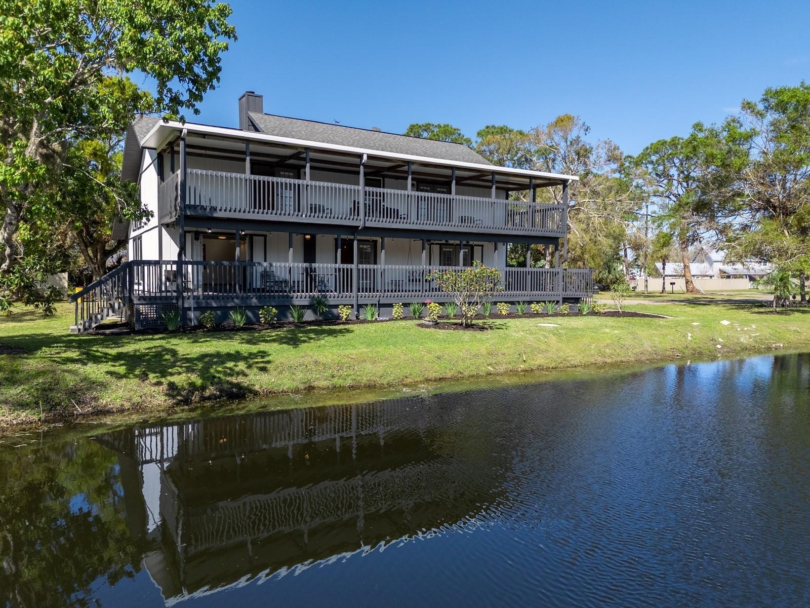 Under contract-accepting backup offers. One or more photo(s) has been virtually staged. A private lakefront retreat nestled on 1.8 acres right in the heart of Sarasota! This serene sanctuary provides the perfect blend of seclusion and accessibility, inviting you to escape the hustle and bustle while being close to all the amenities you need. Located west of I-75, near Cattleman Road, this property has 4-5 bedrooms, a den/study, 3 bathrooms, and a detached, climate-controlled 1500 square foot garage that accommodates 4-5 cars, offering endless possibilities. The hobbyist will find it a versatile workshop, while the visionary can adapt it to meet their needs, enhancing its potential and value. The main house has a wraparound porch surrounding the first floor, featuring three French doors blending the indoor and outdoor spaces. A great room combines living and dining areas and boasts clerestory and twin picture windows, two-story ceilings, and a wood-burning fireplace. The kitchen is fully equipped with nearly new stainless-steel appliances from GE. It has ample cabinetry designed in a farmhouse style, complete with stained glass accents. Additionally, there is a built-in pantry and under-stairs storage for even more convenience. A center island on tiled flooring includes a breakfast bar and extra cabinets for added organization. A separate den/study has double pocket door privacy, window bench seating, and direct access to one of two primary bedrooms. This first-floor suite overlooks the lake and has a built-in closet. This wing also includes a flex room that could be converted into a beautiful walk-in dressing closet (refer to the virtually staged photo). The updated bath has room for an enlarged vanity to accommodate double sinks. This area could be transformed into the ideal first-floor Owner’s suite by integrating these rooms with continuity. A landing on the second floor leads to the bonus room, which overlooks the main living area. The primary suite on this floor has been upgraded and features a balcony and a walk-in closet. A stylish barn door separates the en suite bathroom, which includes a free-standing vanity, dual sinks, and a spacious walk-in shower with a glass door. Upstairs is an updated bathroom and two additional bedrooms, each featuring a walk-in closet, a laundry room, and French doors to a balcony. Step onto one of the two decks to experience stunning sunrises over the lake. The lower deck has just been reinforced and refurbished. The house is said to contain a 3-foot concrete block wall and concrete pads supporting steel floors and beams, originally built to accommodate these beams for added structural support. Surrounded by stately oaks on an expansive piece of land, this remarkable home offers plenty of room for outdoor activities and the possibility of adding a pool without any deed restrictions. So, bring your boat and RV! The location is near Detweiler’s Farm Market, UTC shopping, and various dining destinations. It is also close to several county parks, including the Celery Fields, which borders Ackerman Park. This 360+ acre area is well known to locals for its diverse wildlife and wetlands, providing opportunities for nature watching and exploration. Visitors can enjoy activities such as walking along two boardwalks, fishing, and kayaking.