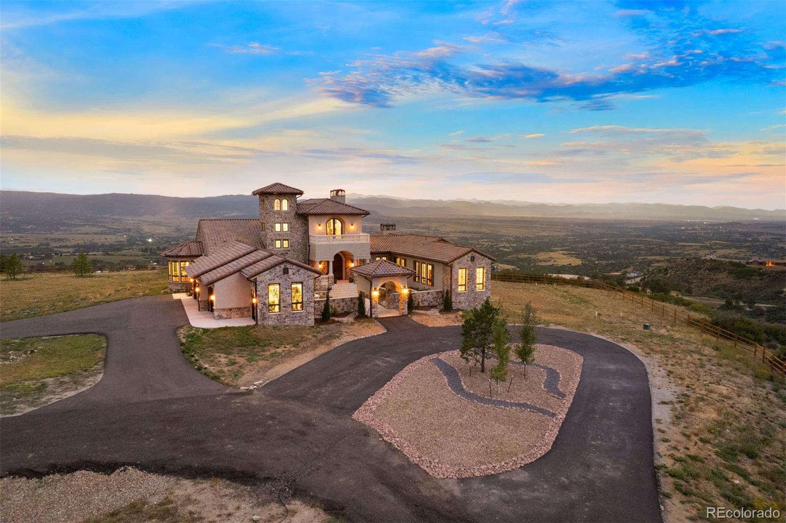 Some homes feel like a destination—this one feels like a calling. A place that pulls you in with its stillness, holds you with its design, and feels both transported and deeply rooted in its setting. Set atop a secluded mesa with dynamic topography and a private pond, this newly built Mediterranean-inspired estate offers an extraordinary vantage point, with the entire Front Range, Pikes Peak to Longs Peak, visible from every window. On over 35 acres in one of Castle Rock’s most exclusive gated communities, the home draws from authentic Italian architecture: stone arches, a courtyard, and stately columns that define its expansive outdoor living spaces. Feels like Italy. Looks like Colorado. Lives like nowhere else.

Symmetry is a hallmark of the design, creating balance and rhythm, and it all converges in the great room. Vaulted ceilings with beams, towering arched doors, and a cast concrete fireplace bring proportion and warmth, while expansive windows frame the ever-present mountain backdrop. The kitchen is anchored by two oversized waterfall islands and surrounded by floor-to-ceiling cabinetry, JennAir appliances, and thoughtful touches like a built-in Miele coffee maker and Italian wine window. Outdoor spaces are designed for year-round use, with arched stone columns, a curved viewing balcony, tongue-and-groove ceilings, and a lower patio wired for a hot tub.

Main-floor living includes a mountain-view primary suite with private balcony, a two-sided fireplace, spa-worthy bath, and expansive walk-in closet. A guest suite, office, and mudroom with pet wash add everyday ease. Above, the crow’s nest offers a flex space with twin balconies—ideal for work, creativity, or quiet retreat. The walkout lower level features a recreation room with fireplace, wet bar, gym, and 2 bedrooms. And through it all, with the kind of quiet that only comes from open land and long views, it lives like the Italian countryside—but looks out over Colorado’s most iconic skyline.