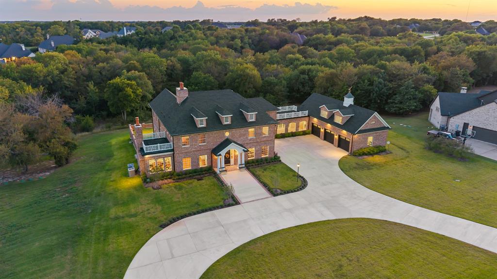 Step into timeless elegance with this one-of-a-kind Georgian Colonial estate, masterfully designed with craftsmanship and sophistication at every turn. Nestled on a serene, tree-lined 2-acre lot, this custom home welcomes you with a grand circle drive and stunning curb appeal, setting the tone for the refined luxury within.  Inside, you’ll find rich custom woodwork, exposed brick accents, and an abundance of natural light that fills every room. The chef’s kitchen is a culinary dream, featuring a massive prep island, top-tier appliances, and a walk-in appliance pantry designed for both beauty and functionality. Enjoy morning coffee in the sun-drenched solarium, or unwind with a good book in the private home library. The expansive executive office offers an inspiring setting for the most discerning professional—ideal for hosting meetings or managing business affairs in style.An in-home elevator provides effortless access to every level, including spacious attic storage. Step outside to experience multiple patios and balconies overlooking the peaceful, wooded estate—perfect for entertaining or quiet reflection. A brick-laid breezeway connects to the oversized three-car garage, completing this remarkable property that seamlessly combines grandeur and comfort. This home is truly a rare find—a timeless statement of design, privacy, and luxury living in the heart of McKinney. Versa lift in garage; attic above garage is unfinished bonus room 48x13; elevator to second floor and attic on third floor; brick floors; Documents listing the many features can be found in Transaction Desk; double lot allows for addition of a pool house with guest quarters but not a second residence.