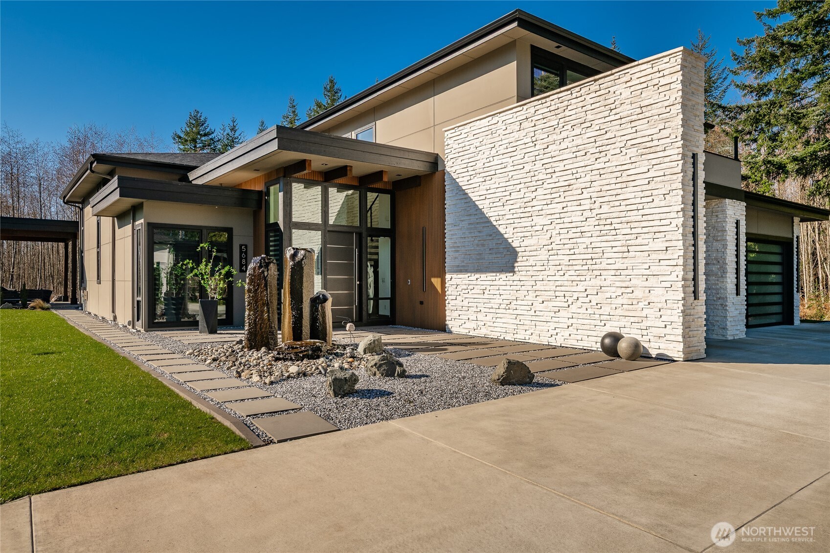Exceptional modern residence in the coveted Semiahmoo community, offering 3,397 sq ft of refined design on a private 14,375 sq ft lot backing to serene wooded surroundings. Floor-to-ceiling Westeck windows fill the main living spaces with natural light while showcasing seamless indoor-outdoor living. The chef’s kitchen features exquisite cabinetry, Black Line Kitchen-Team 7 walnut, colored glass matte black smoked, imported by Austria & paired with premium Gaggenau luxury kitchen appliances. Opulent details continue throughout, including a striking book-matched porcelain fireplace feature wall, three sophisticated wet bars, and spa-inspired baths. The primary suite is a private retreat with a freestanding soaking tub, dramatic dual-entry shower wrapped in porcelain thin slab, and direct access to a secluded patio with hot tub. Outdoor living is equally impressive with a covered entertaining pavilion, outdoor kitchen, stone fireplace, water feature, and beautifully designed hardscaping—all set against a peaceful natural backdrop. A truly exceptional custom home blending modern architecture, luxury finishes, and Northwest tranquility.