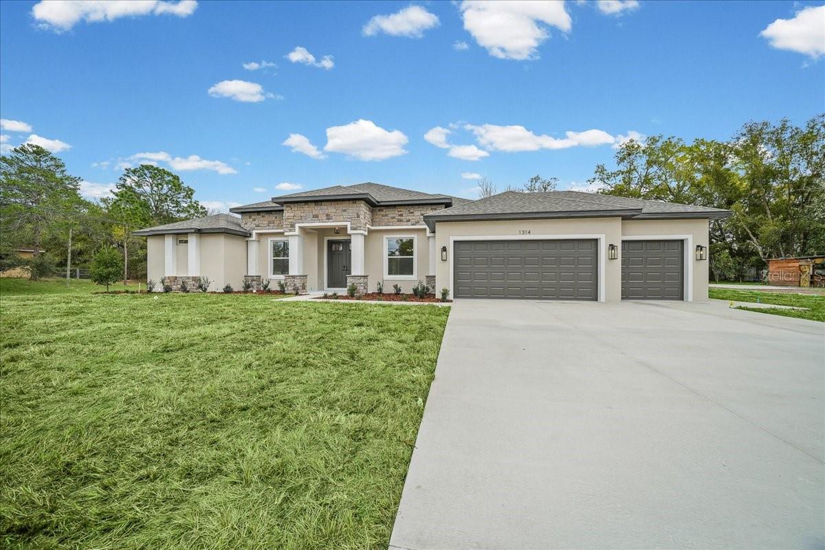 Welcome to The Jubilee—a stunning new construction home that blends modern style with everyday comfort. Situated on a beautifully cleared corner lot in Spring Hill Florida, this rare find offers 5 bedrooms, 3 bathrooms, and an oversized 3-car garage, all thoughtfully designed with premium upgrades throughout. From the moment you arrive, the home’s impressive presence and landscaped setting set the tone. Step through the grand double doors into a beautiful foyer with elegant tray ceilings that showcase the home’s craftsmanship and attention to detail. The bright, open-concept floorplan creates the perfect balance of comfort and functionality, seamlessly connecting the living room, kitchen, dining area, and a versatile fifth bedroom that works beautifully as a home office, playroom, or guest suite.At the heart of the home is a  kitchen designed for both everyday living and entertaining. It features quartz countertops, soft close cabinetry, a large center island with barstool seating, generous counter space, and pantry storage. Just off the kitchen, the dining area provides the ideal space for casual meals or hosting guests. Sliding glass doors open completely to a spacious covered back porch, creating a true indoor-outdoor entertaining experience. The patio is already pre-plumbed for a full outdoor kitchen, and the layout was thoughtfully designed with space for a future pool. For added convenience, a bathroom connects directly to the outdoor area.The luxurious primary suite offers a private retreat with tray ceilings, a large walk-in closet, and a spa-inspired bathroom featuring a stand-alone soaking tub, oversized step-in shower, and dual-sink vanity. The split floorplan ensures privacy, with three additional bedrooms and two bathrooms located on the opposite wing of the home, providing comfort and space for family and guests.Throughout the home, luxury vinyl flooring delivers durability while enhancing the modern aesthetic. Additional highlights include a spacious laundry room with direct garage access and a built-in mudroom area, plus pre-wiring in the garage for an additional refrigerator.Located just minutes from the Veterans / Suncoast Expressway, this property offers an easy commute while still providing the space and tranquility of country living. With no HOA, a full acre of land, a sprinkler system already in place, and endless possibilities for your dream backyard, this home truly stands out. Modern design, premium finishes, and room to live, entertain, and grow—The Jubilee is a home you won’t want to miss.