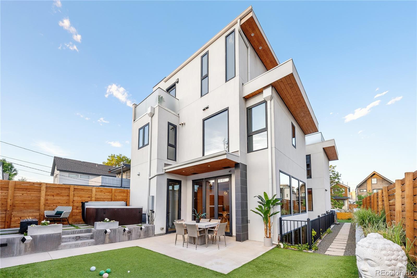 For the first time ever, the final residential project of internationally acclaimed artist Lawrence Argent, creator of Denver’s iconic Blue Bear, comes to market in the heart of LoHi. Conceived in collaboration with award-winning Lubowicki Architecture, this deeply personal architectural residence was designed around light, scale, warmth, and privacy.Created under previous zoning allowances difficult to replicate today, the home captures sweeping Denver skyline views, soaring ceilings, and exceptional indoor-outdoor living. A striking slate-clad architectural spine rises through the home, culminating at the rooftop terrace overlooking the city skyline.Massive exposed timber beams, steel detailing, and floor-to-ceiling south-facing glass define the main living spaces, while a floating staircase connects all levels. A 12-foot folding glass wall opens the dining area to layered backyard terraces and outdoor living spaces.Unlike a traditional basement, the lower level features 10-foot ceilings, polished concrete floors, and direct access to a private sunken garden terrace. Extensive sound-mitigating construction, including specialized triple-wall assemblies, creates a remarkable level of quiet and privacy rarely experienced in attached residences. The home was intentionally designed so windows and living spaces open toward light, outdoor areas, and skyline views rather than neighboring walls.The chef’s kitchen features custom walnut cabinetry, integrated DÉCOR appliances, waterfall quartz surfaces, and dual entertaining bars.The entire upper level lives like a private penthouse retreat, featuring skyline views, a 12-foot sliding glass wall opening to the rooftop terrace, and a spa-inspired bathroom with heated floors, steam shower, skylit soaking tub, oversized shower, custom walnut dual vanity, and a private sunset balcony off the primary closet.Rarely does a residence of this architectural significance, privacy, and design quality come to market in LoHi.