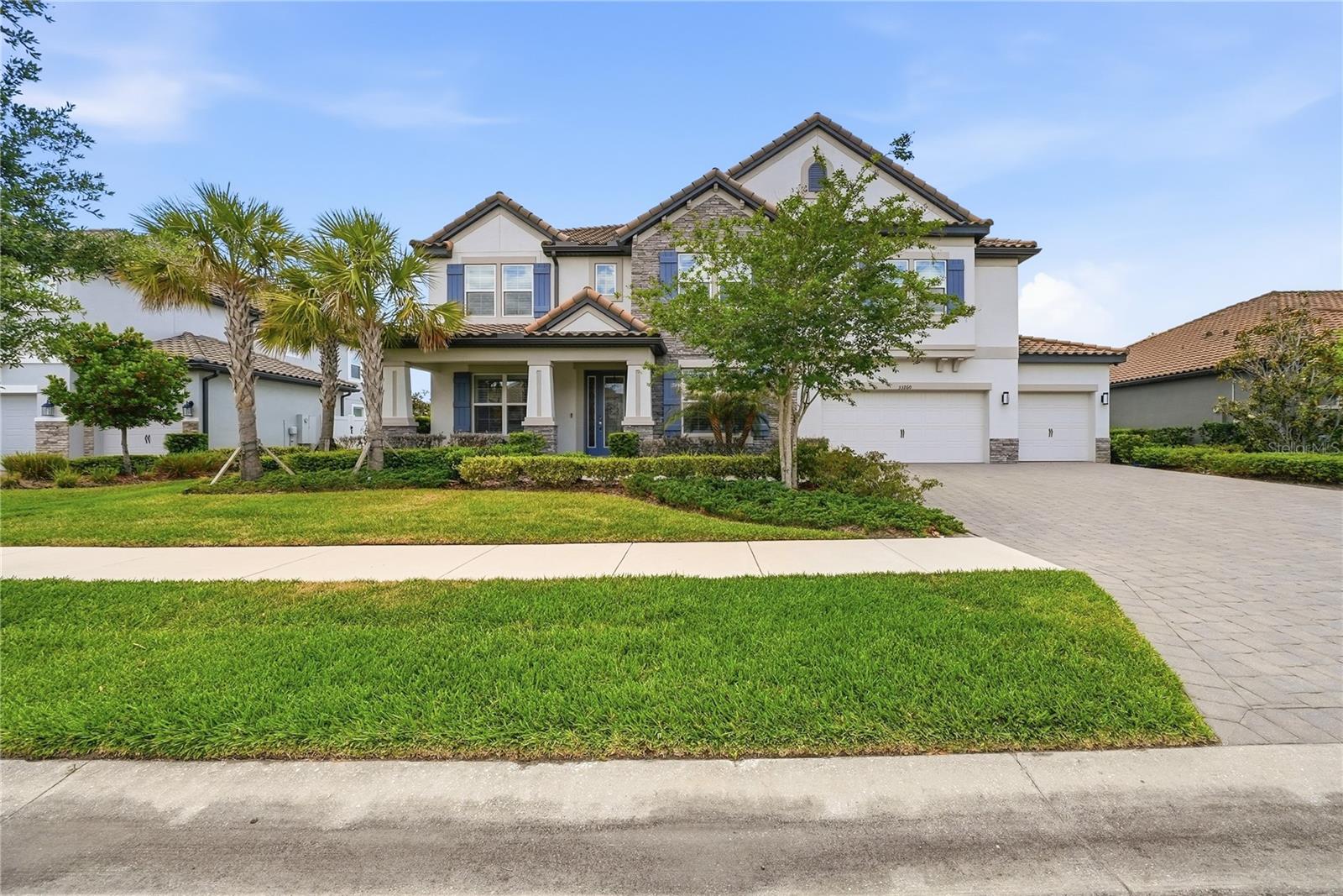 Stunning and well maintained grand residence with an abundance of luxurious features and upgrades in the gated Graybrook neighborhood of the WaterGrass community. This exquisite six-bedroom, four-bath, five-car garage pool home is a craftsman masterpiece and was built in 2022. This property boasts a generous 4,773 square feet of living space with an extremely well-designed floor plan including an office, an enormous bonus loft and multiple flex areas. The home’s stone accented exterior elevation exudes timeless sophistication, welcoming you with a grand entrance and open porch. Inside, motorized shades in the living area provide effortless control of natural light while enhancing the ambiance. The living area features gorgeous wood and porcelain accented feature wall with a built-in electric fireplace, creating a focal point that is cozy and stylish. The gourmet kitchen is a chef's delight, showcasing an oversized dual waterfall quartz island that is visually striking. The large walk-in pantry offers plenty of storage, while the dry bar with a beverage refrigerator serves as a coffee bar, and built-in GE Profile convection oven and microwave provide convenience and elegance for entertaining guests. The GE Profile electric cooktop with a range hood, white subway tile backsplash, hidden cabinets under the bar, and smart and touch-activated inlayed sink are just a few of the distinctive features this kitchen has to offer. Additionally, an extra butler's pantry provides added convenience for preparing meals and hosting events. Indulge in luxury in the primary suite, offering dual walk-in closets and a spa-like haven for a primary bedroom, complete with a water closet, a generous linen closet, a frameless glass walk-in shower, a separate deep soaking bathtub and a split dual vanity with makeup counter. Entertain in style with the large media room, with surround-sound speakers, and a high-quality projector screen for a true cinematic experience. The oversized loft at top of the stairs offers additional flexible space or relaxation zone. The property boasts ample custom trim and millwork, including crown molding, tray ceilings and feature walls, adding a level of refinement throughout the home. Upgraded LED recessed lighting, hanging light fixtures and plumbing fixtures complement the elegant design, creating a warm and welcoming atmosphere. Step into the backyard, and you'll find an oasis, providing year-round relaxation and recreation with the screened-in heated saltwater pool boasting three cascading waterfalls and two elegant fountain jets. Lounge in style on the two tanning ledges, each with removable umbrellas, or unwind in the luxurious spa after a long day. Enjoy privacy and security in the sprawling fully fenced backyard, providing a safe environment. The rare five-car garage with hanging storage and a convenient workbench is perfect for the car enthusiast or anyone in need of ample storage space. Located in the gated Graybrook neighborhood of the WaterGrass planned community offering additional amenities and community pool, as well as Watergrass Elementary School and fire department. With nearby interstate access, this growing area has the sought-after Innovation Preparatory Academy and Kirkland Ranch Academy of Innovation while close to shopping and dining of the Tampa Premium Outlets and Shops at Wiregrass.