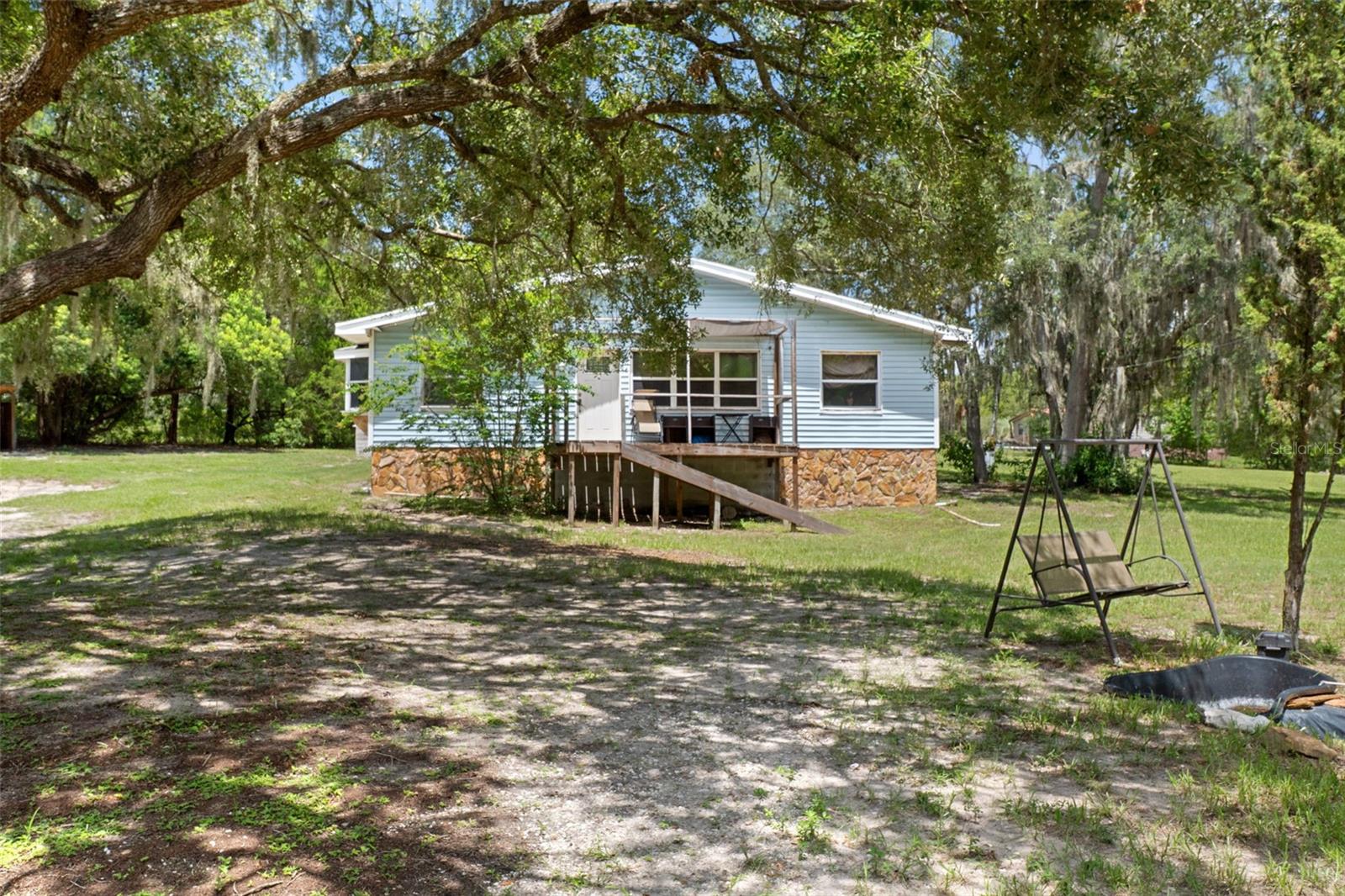 Escape to your own private country retreat with this charming 3-bedroom, 2-bathroom home offering 1,550 square feet of comfortable living space on a secluded 2.5-acre lot in Brooksville, FL. Surrounded by mature trees for exceptional privacy, this inviting home features an open floor plan with abundant natural light, while the living room showcases a stunning floor-to-ceiling stone fireplace with a built-in mantel. The spacious kitchen blends rustic charm with modern convenience, showcasing wood and stone-look accent walls and built-in dual ovens. The kitchen also features built-in shelving, a built-in dining table, stainless steel appliances, a smooth-top range with range hood, generous counter space, and ample cabinetry. Warm wood-grain vinyl flooring and ceiling fans throughout enhance the home's cozy, country-inspired aesthetic. The primary suite features beautiful bay windows that fill the space with natural light, creating a bright and airy retreat, along with a walk-in closet and en-suite bathroom. The en-suite bathroom features an extended vanity with abundant lower cabinetry and a charming white brick backsplash accent behind the toilet. Additional highlights include a separate laundry room with built-in shelving, an above-ground pool, covered front and back porches, a storage shed, a covered workshop area, and wire fencing. While the home could benefit from a little TLC, many of the major updates have already been completed, including a brand-new roof, as well as the HVAC system and septic system having been updated within the past few years, allowing the next owner to focus on adding their own personal touches while enjoying the many unique features, spacious acreage, and peaceful setting already in place. Enjoy the best of country living without sacrificing convenience, with shopping, dining, and everyday amenities just 20 minutes away. Ideally located for both relaxation and adventure, this home is approximately 20 minutes from Weeki Wachee Springs State Park, 30 minutes from Pine Island Park and beach, and less than 60 miles from Tampa, giving easy access to outdoor recreation, Gulf Coast beaches, shopping, dining, and city amenities. Offering the perfect blend of privacy, rustic charm, and easy access to recreation, this property is ready to become your own private escape. Buyer's agent to verify all measurements.