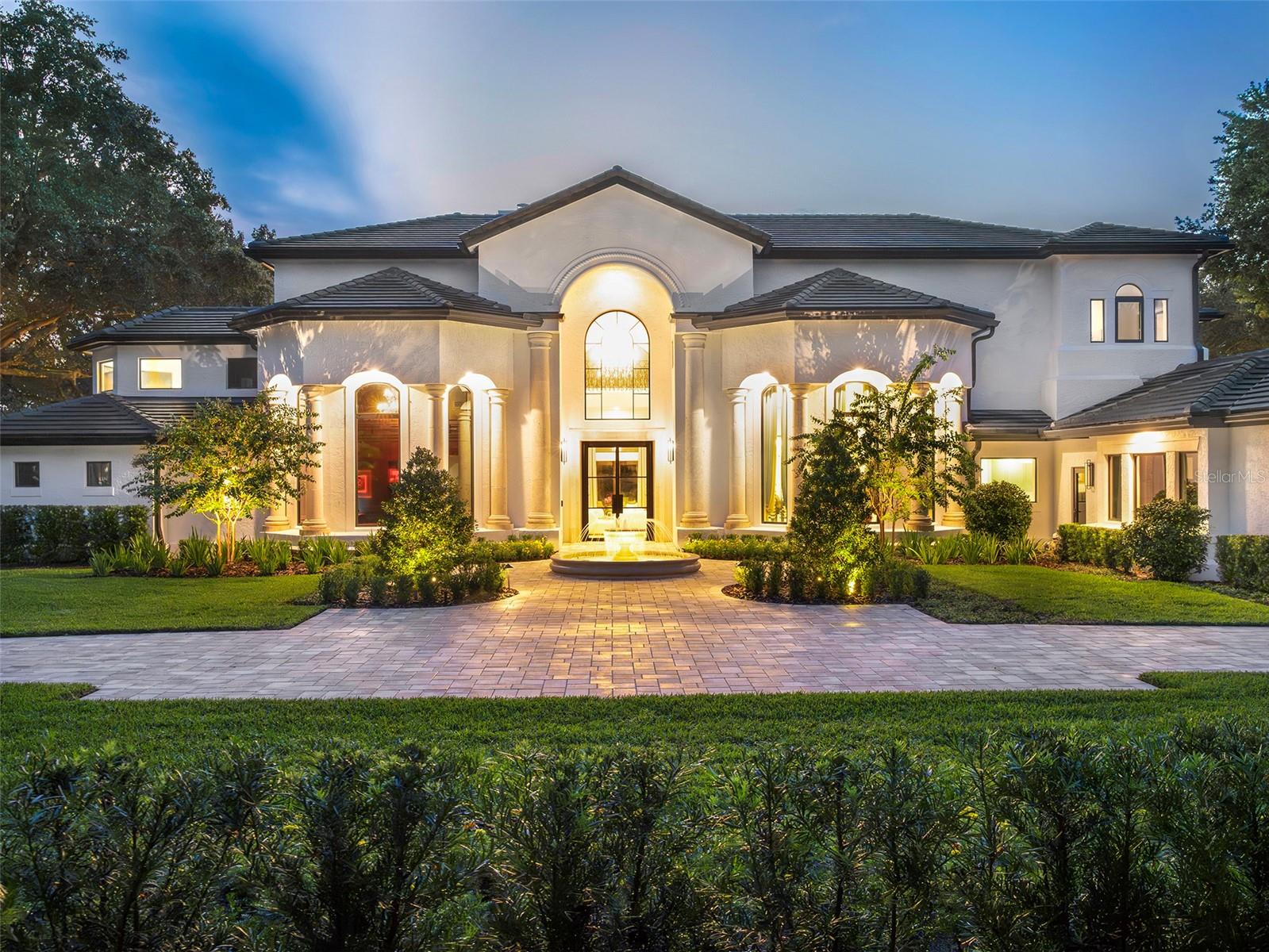 Set along the front nine of Isleworth championship golf course with breathtaking views of Hole 6, this grand estate occupies an oversized lot along Isleworth’s main drive and has been beautifully reimagined with an extensive transformation over the last two years. The result is a sophisticated, move-in-ready home where timeless architectural character blends seamlessly with thoroughly modern style.Originally built by Pellegrini Homes and expanded to 7,100 square feet, the residence retains its signature architectural details, including custom ceilings, travertine floors with intricate tile inlays, and carefully crafted shell stone columns. The grandeur of the formal living room is accentuated by its soaring 20-foot ceiling, magnificent chandelier, and stately stone fireplace. A former bonus room has been thoughtfully transformed into the home's impressive new chef's kitchen, featuring custom cabinetry, an Italian-made 48-inch ILVE range, a luxury appliance collection, and elegant finishes. The original kitchen has been reimagined as a sophisticated entertaining bar with custom cabinetry, a built-in espresso cabinet, wine storage, and dedicated space for morning coffee and smoothies. Both spaces connect effortlessly to the casual dining area and formal dining room, creating an exceptional flow for everyday living and entertaining. The family room offers an open, airy setting with a built-in media display and effortless connection to the lanai.The main-level owner's suite provides a private retreat with a cozy fireplace, dual closets, and a lavish bath featuring dual vanities, a walk-in shower, and a luxurious soaking tub framed by elegant stone columns. A new main-level bedroom with private en-suite bath and an enlarged loft suite add flexibility for family and guests. Throughout the residence, new flooring, custom cabinetry and built-ins, designer lighting including bespoke Italian Murano glass fixtures, custom drapery, automated shades, and beautifully appointed furnishings create a cohesive, elevated aesthetic. Custom London-made closet lighting adds another layer of thoughtful detail, while modernized infrastructure, integrated technology, whole-home Wi-Fi, security, and smart-home features provide a seamless foundation for today's lifestyle.Outside, the residence has been transformed into an exceptional setting for both relaxation and entertaining. The pool has been resurfaced, outdoor living areas expanded, and a new outdoor kitchen and grilling area added, while a completely redesigned landscape, lighting, fencing, and fountain features enhance the grounds. Upstairs, the bedroom suites and expansive balcony capture panoramic views of the golf course and sparkling waters of Lake Bessie. The European-style lanai, with its graceful balustrade, creates an inviting setting for al fresco gatherings and captivating sunsets.This exceptional estate offers a rare combination of timeless architectural character, comprehensive modern improvements, sophisticated design, and an enviable golf-front setting within Isleworth.