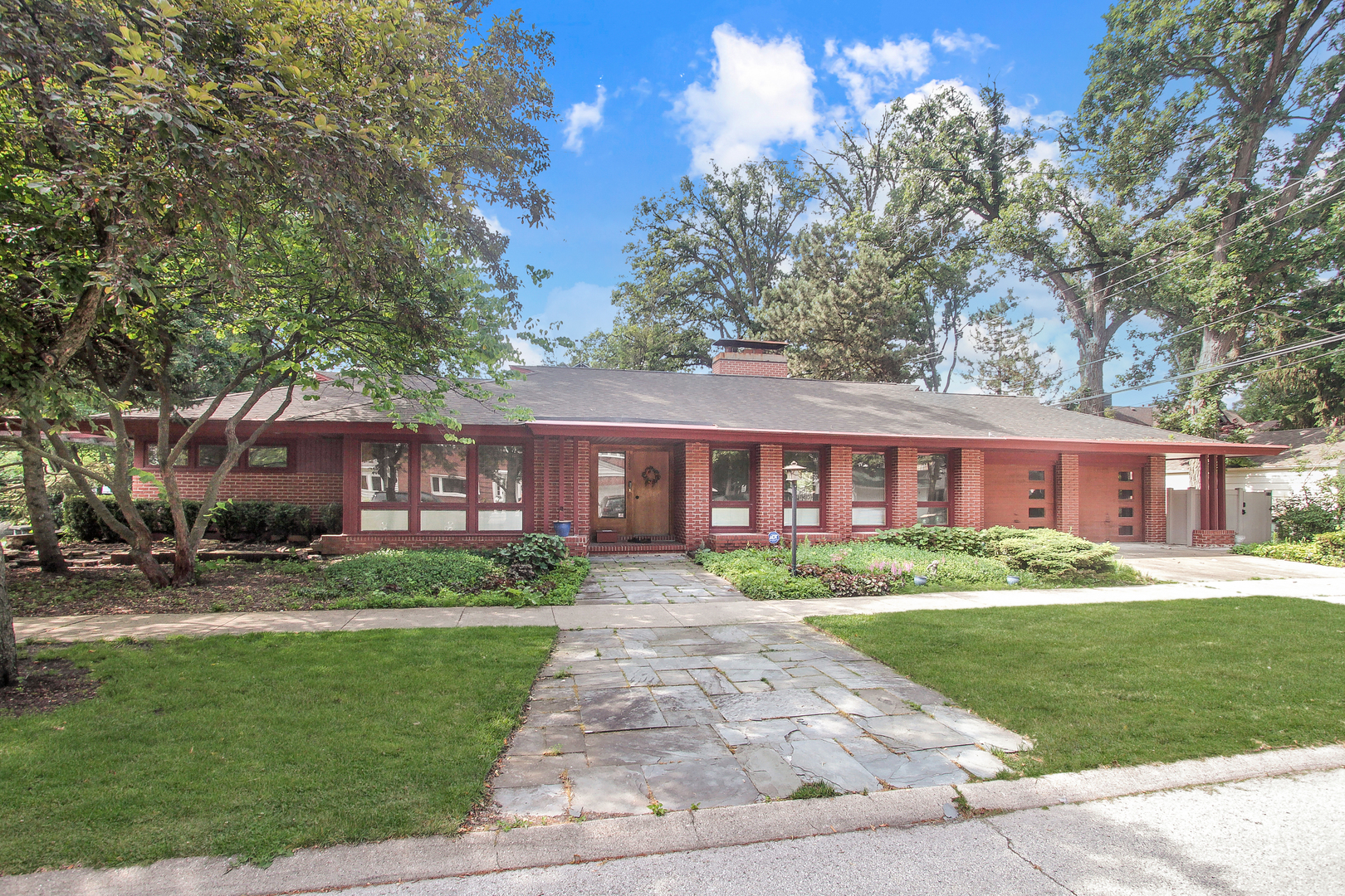 A true architectural treasure, this sprawling 3-bedroom mid-century modern ranch was custom-built by renowned architect Charles Stade for his own family. The home features an open floor plan anchored by a striking central hearth fireplace, custom wood trim and built ins, exposed brick interior, and walls of natural light. The beautiful kitchen features granite counters and high end appliances and is open the sunroom and sliders to the back patio - perfect for relaxing or entertaining. There's a large living room with a wall full of windows to let in the light, two large bedrooms and a flex room that could be used as an office or a bedroom. Nothing to do here but move in and enjoy!