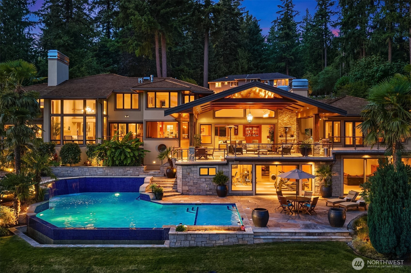 Welcome to Rockmeadow Farms. Set at the end of a private cul-de-sac behind secure electronic gates, this extraordinary 8,750-square-foot Northwest Contemporary estate rests on 0.81 private acres, offering resort-style living in complete serenity. A cascading rock waterfall & koi pond welcome you to double mahogany doors, opening to a dramatic two-story foyer, wrought-iron bridge balcony & vaulted great room framed by floor-to-ceiling windows showcasing panoramic, unobstructed views of Lake Sammamish & the Cascade Mountains.  Designed for effortless entertaining, the chef’s kitchen features Wolf, Sub-Zero & Miele appliances, a multi-level granite island & integrated sound. Disappearing pocket doors open to a covered timber-frame pavilion with skylights, infrared heaters, outdoor TV, stone fireplace & built-in BBQ kitchen.  A rare main-level primary sanctuary features a private view balcony, chandelier-lit dressing room & spa bath with sunken soaking tub overlooking the lake. An executive office/den with private deck access & full bath offers the opportunity for a secondary primary or multigenerational suite on the main. Three additional bedrooms are upstairs. The lower level delivers a gym, sauna, wet bar, wine cellar, media lounge & pool access.  Terraced gardens descend to a heated saltwater pool with cascading waterfalls, sunken hot tub & masonry fire pit. Mature landscaping, hummingbirds, nesting eagles & occasional deer complete this private Pacific Northwest retreat.