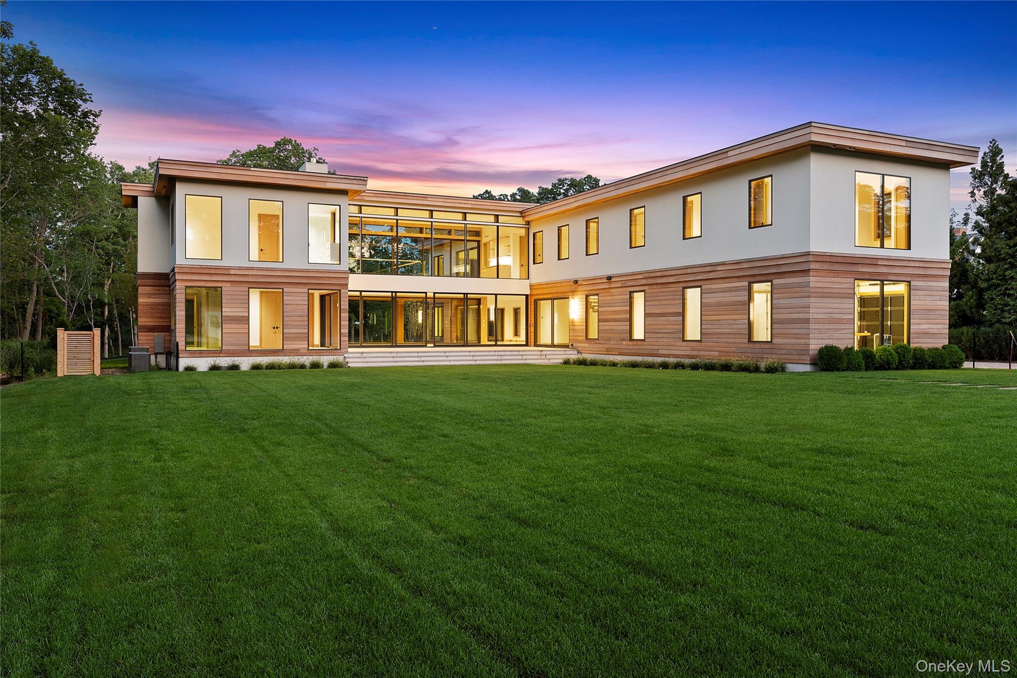 Set on more than 3.7 acres in North Haven, this brand-new estate combines architectural elegance with the relaxed spirit of Hamptons living. Thoughtfully designed to frame open views of Fresh Pond and Sag Harbor Bay, the property offers both a sense of privacy and easy access to the best of the area - just minutes from Sag Harbor Village, beaches, marinas, and waterfront dining. The 8,960 SF residence unfolds across three levels, blending striking scale with comfortable flow. A soaring double-height entry sets the tone, leading to a sunlit great room with walls of glass and a stone fireplace. The chef's kitchen, outfitted with marble counters, a full butler's pantry, and high-end appliances, connects seamlessly to indoor and outdoor dining areas through electronic glass doors. The main level also features a junior primary suite with spa-style bath, an additional living room with fireplace, home office or sitting room, laundry, mudroom, and access to the attached two-car garage. Upstairs, the primary suite enjoys sweeping water views, dual walk-in closets, and a resort-like bath with soaking tub and steam shower. A private sitting room or office with full bath extends the suite. Five guest bedrooms, each with en-suite baths and walk-in closets, share the second floor alongside a lounge with wet bar and terrace overlooking the property. The grounds are designed for leisure and entertaining, anchored by a 20' x 50' heated saline pool with integrated spa. A separate 320 SF pool house with kitchenette and firepit adds convenience and charm. Expansive rolling lawns, limestone patios, mahogany terraces, and the possibility of adding a tennis or pickleball court make the outdoor spaces as versatile as they are beautiful. Mature landscaping and perimeter hedges ensure peace and privacy. 27 Fresh Pond Road offers the rare combination of cutting-edge design, resort-level amenities, and a coveted North Haven location The main level spans 4,720 SF and welcomes you with a dramatic double-height foyer and custom white oak floating staircase. At its heart is an open chef's kitchen with marble counters, a center island with seating, all high-end appliances, and a full butler's pantry. Electronic glass doors seamlessly connect the dining area to two covered porches, while the soaring great room boasts floor-to-ceiling windows and a stone-clad fireplace. This level also includes a junior primary suite with porch access, dual walk-in closets, and a spa-like bath, plus a sitting room/office, second living room with fireplace, powder room, laundry with dual washer/dryers, mudroom, and direct access to the garage. Upstairs, the 4,240 SF second level offers a private primary suite with water views, two walk-in closets, and a luxurious bath featuring a soaking tub, steam shower, dual vanities, and private water closet. A connected sitting room or office includes its own full bath. An upper lounge with wet bar opens to a terrace overlooking the grounds, while the guest wing provides five additional en-suite bedrooms, each with walk-in closets. A second laundry room completes the level. Designed for entertaining, the 320 SF pool house offers a kitchenette, two outdoor seating areas, and a built-in gas firepit. The outdoor setting is anchored by a 20' x 50' heated saline gunite pool with integrated spa, surrounded by limestone patios, mahogany-covered terraces, an expansive rolling lawn, and room to add a tennis or pickleball court. The grounds are enhanced with lush landscaping and mature hedges for privacy. With its thoughtful design, resort-style amenities, and tranquil North Haven setting, 27 Fresh Pond Road is the perfect retreat for year-round living or an elevated seasonal escape.