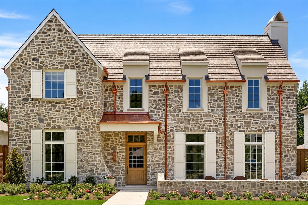 6526 Woodland Drive is a new construction residence by Mosaic Building Co. with McLean Interiors and Briggs Architecture & Design, blending timeless materials with modern functionality in the heart of Preston Hollow. A striking natural stone exterior, synthetic cedar shake roof with copper accents, limestone porch cladding, and a custom white oak entry door with leaded glass establish understated elegance. Inside, white oak wide-plank hardwood flooring and millwork, lime-washed living room walls and ceiling, and custom iron stair railings create a warm, architectural palette. Designed for everyday living and entertaining, the main level offers exceptional sightlines between the dining room, kitchen, living room, and lounge, while floor-to-ceiling windows fill the home with natural light. The secluded downstairs primary suite features vaulted ceilings and a spa-inspired bath with heated natural stone floors, marble finishes, a standing shower, and freestanding soaking tub. Four additional upstairs bedrooms each include ensuite baths and walk-in closets, along with a spacious game room and second laundry room.The kitchen combines craftsmanship with professional-grade performance, featuring a 48-inch Wolf range, custom brass hood, marble countertops, a butler’s pantry, walk-in pantry, built-in breakfast banquette, expansive island, and paneled appliances. Soft-close inset cabinetry and white oak detailing continue throughout. Outdoor living includes motorized patio shades, recessed heaters, a built-in grill with refrigerator, masonry fireplace, wood storage, and gas connection for a future courtyard fire feature. Additional highlights include Lutron lighting controls, trimless recessed lighting, AV prewire, two-stage Lennox HVAC, two Navien tankless water heaters, decked attic storage, and an oversized rear-entry garage with epoxy flooring and an automatic sliding gate. Every detail reflects enduring materials, thoughtful craftsmanship, and livable luxury