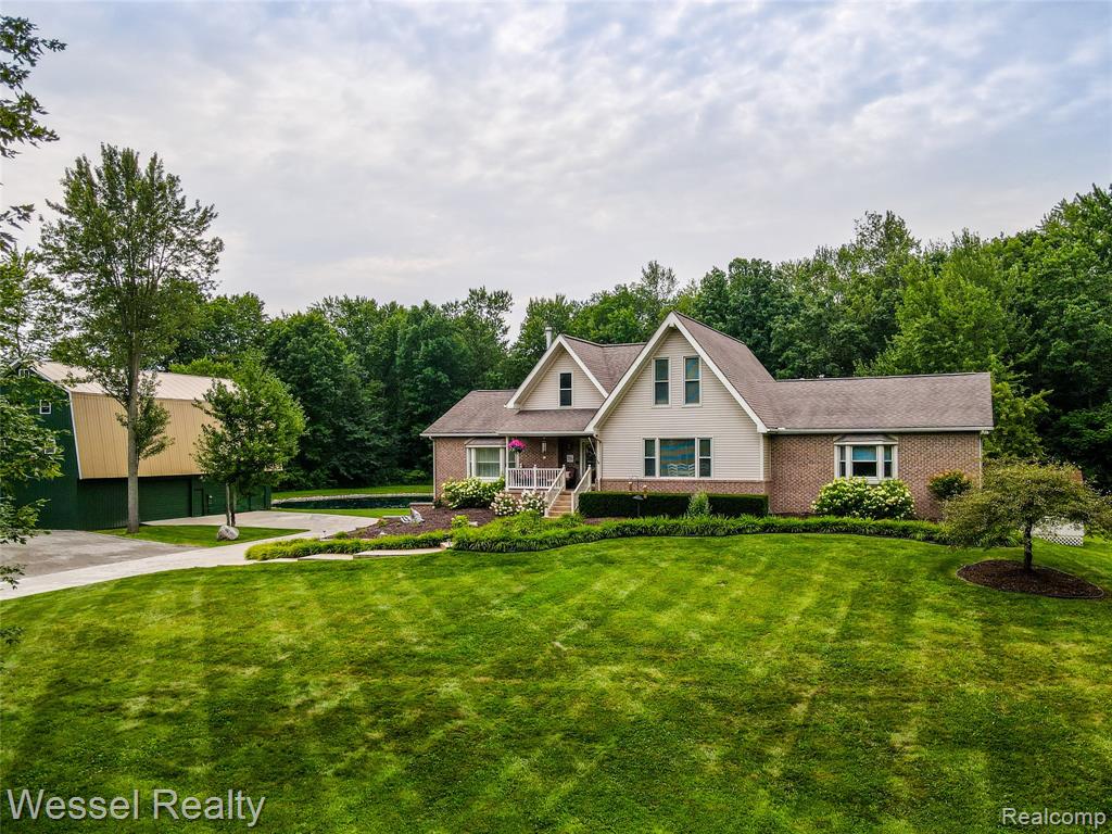This impressive 6-bedroom, 4-bath brick and vinyl ranch with walkout finished basement is set on 5.18 private, wooded acres featuring a spring-fed pond with beach area—perfect for swimming and fishing. A spacious 30x60 four-story pole barn with 240V electric and gas line, plus a 22x46 cement pad for trailer, boat, or RV parking, adds incredible versatility. Built with mostly 2x6 construction, the home boasts a stunning new white kitchen (2024) with quartz countertops, large breakfast bar, expansive dining area, built-in desk, and stainless-steel appliances. The great room features a cathedral ceiling, gas log fireplace, and dual door walls opening to a large deck with picturesque views. The oversized primary suite includes a walk-in closet, laundry, private deck access, and a brand-new luxury bath with walk-in shower and corner jacuzzi tub. The finished walkout basement makes a perfect in-law suite, complete with a full second kitchen (2023), stainless appliances, solid surface counters, white cabinetry, second laundry, full bath, sitting area, and additional bedroom currently used as an office. Recent upgrades include a new furnace, A/C, and water heater (2023), Reme Halo air purification system, high-end steam humidifier, 6-person hot tub (2023), new flooring and paint (2023–2024), and seven new door walls (2024) bringing in tons of natural light. Outside, enjoy the stamped concrete patio by the pond, covered front porch, large cement drive, and mature woods teeming with wildlife.