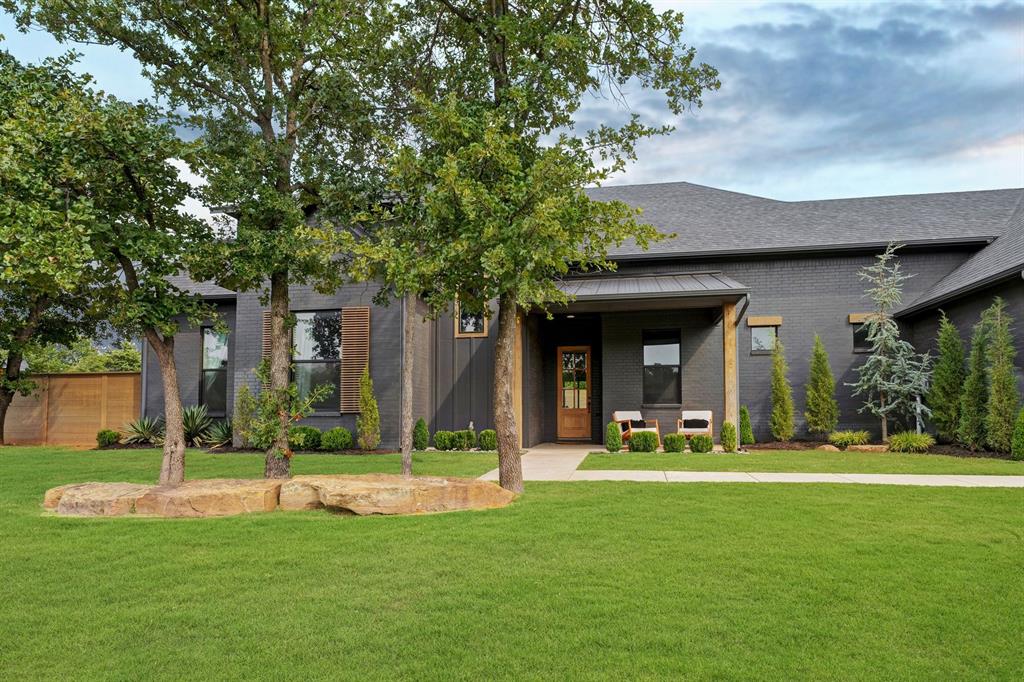 On a generous 3/4 acre lot, this former Parade of Homes property balances scale, function, and style. With five bedrooms, three and a half baths, multiple living areas, a study, chef’s kitchen, 20x30 shop, and private basketball court, it was designed with both everyday living and entertaining in mind. From the entry, thoughtful details begin to unfold—a pocket office tucked neatly off the foyer, a powder bath positioned with guests in mind. The main living area is defined by vaulted ceilings and wide sliding doors that frame the backyard, filling the space with light and creating a natural extension outdoors. The kitchen blends performance and design: professional-grade appliances, a built-in refrigerator, sleek countertops, and a walk-through butler’s pantry. The adjoining dining area, lined with picture windows, is anchored by a sculptural chandelier and built-in buffet. The primary suite offers a spacious bedroom and a bath appointed with dual vanities, walk-in shower, freestanding tub, and understated lighting. The custom walk-through closet connects directly to the utility and mudroom, a practical detail that simplifies daily routines. Three additional bedrooms on the main level share a full bath, each finished with a distinct design perspective. Completing the first floor, a moody bonus room—flexible enough for a fifth bedroom, theater, playroom, or lounge—sits just off the living room. Upstairs, a secondary living area, fifth bedroom, and full bath provide space for guests or family. Outdoors, a covered patio with a fireplace anchors the backyard. Beyond, a playset, trampoline, and basketball court leave room to spare for a pool—turning the property into a true extension of the home.