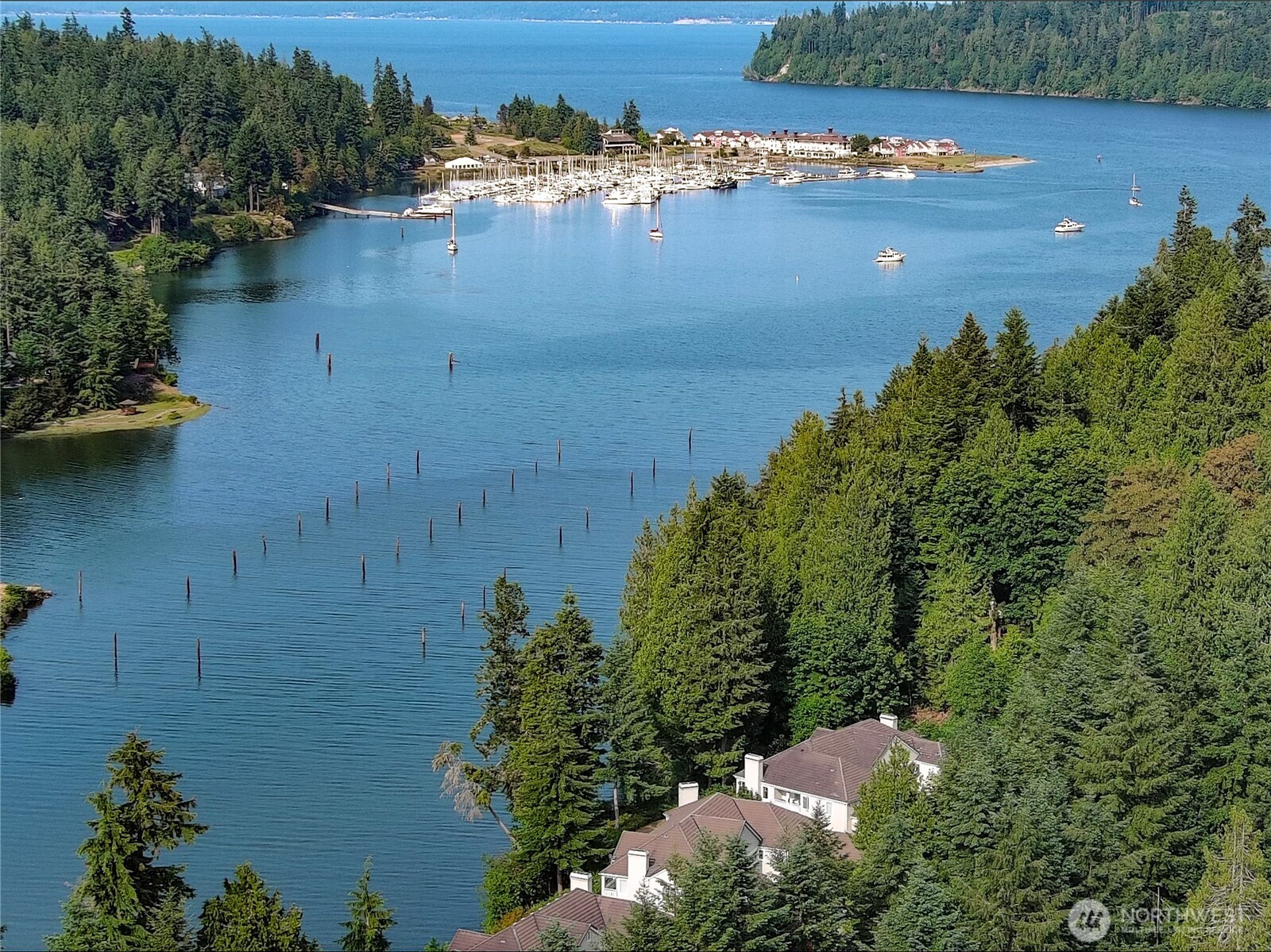 BIG price reduction- an exceptional opportunity to live where others vacation! This waterfront, end-unit condo is now offered at a dramatically improved price, making this lifestyle and location more attainable than ever. Tucked away in a quiet, private enclave, the home enjoys front-row views of the protected bay and surrounding lush forest, creating a peaceful, nature-filled setting where herons, deer, and seagulls are frequent visitors. Inside, thoughtful updates shine throughout, including refreshed kitchen and bathrooms, updated flooring, and modern lighting that enhances the bright, open feel of the home. The spacious open floor plan allows for effortless flow between living, dining, and kitchen spaces- ideal for everyday living or entertaining. Large windows frame the scenery and fill the home with natural light, while modern comforts such as an on-demand water heater add efficiency and peace of mind. An oversized laundry area and attached garage provide rare convenience for condo living. Step outside to the private deck and unwind as you take in tranquil water views and the sights and sounds of nature. All of this is just moments from resort-style amenities, including a clubhouse, fitness center, pool, golf course, dining options, and miles of scenic walking trails. With a significant price improvement, this is a standout value for waterfront living- don’t miss your chance to make it yours.