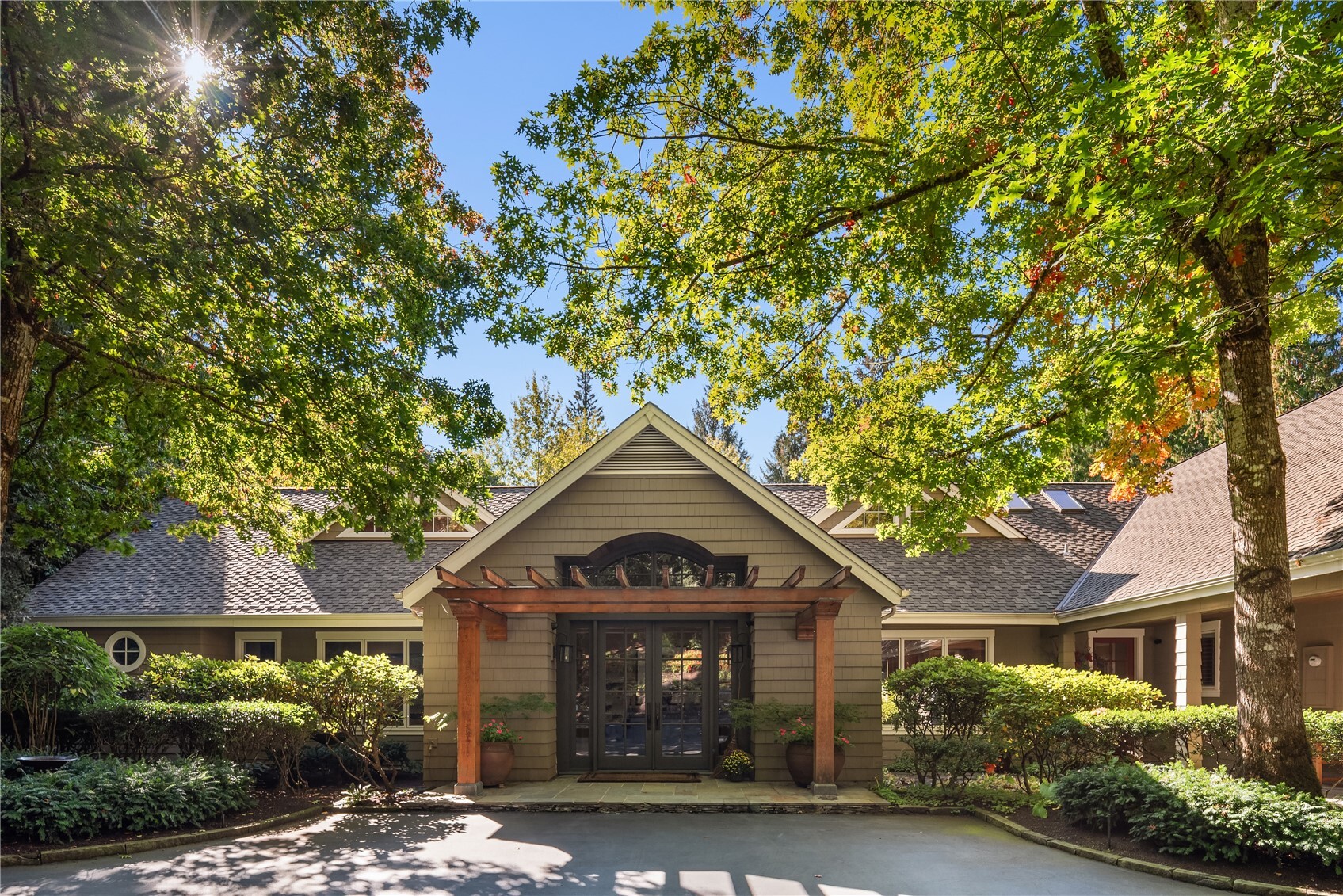 Front entry with timber pergola and glass double doors shaded under trees