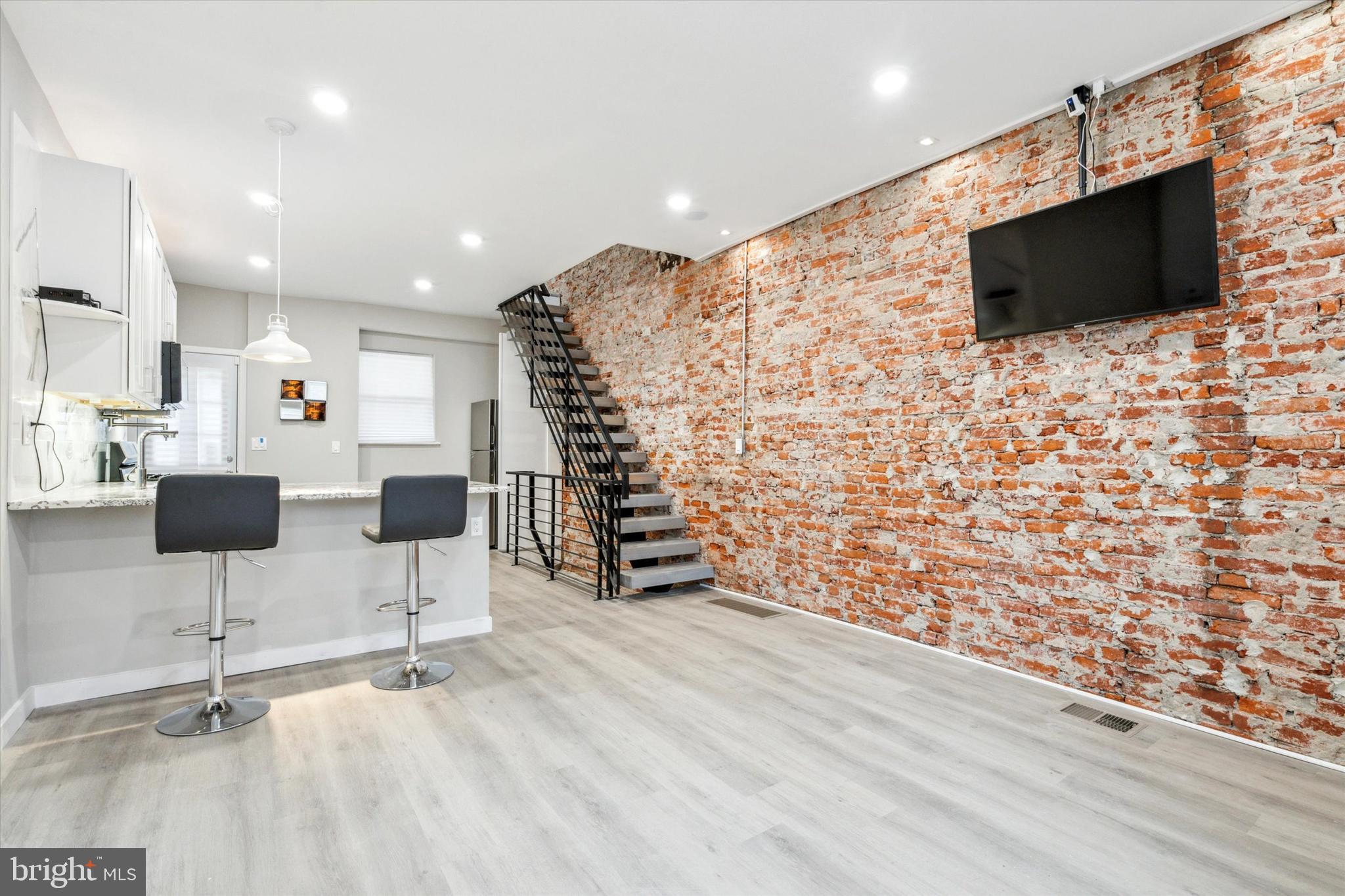 **STYLISH RENOVATED HOME WITH EXPOSED BRICK AND FINISHED BASEMENT**Once inside you will notice the meticulous workmanship that make it feel fresh and new! The open living/dining area framed by exposed brick and a floating staircase are just ready for your furnishings, art and making a truly homey atmosphere.  TV and Barstools pictured are included. The kitchen is a standout with crisp white cabinetry, granite countertops, breakfast bar and new stainless-steel appliances. The patio is a true retreat and is fenced in and ready for your grill and outdoor furniture/plants. The 2nd floor features 2 good-sized bedrooms with ample closet space perfect for creating your own personal sanctuaries. The full hallway bath is modern with wood tile accents and new vanity. As a bonus the basement is fully finished with a fireplace and could feature your 3rd bedroom with egress and half bath allowing for the ultimate extra living/rec or home office space. For park lovers or those with dogs, the proximity to Fairmount Park can’t be beaten. For the commuters out there, entrances to I-76 East and West and local bus stops to Center City are just minutes away. Convenience meets charm in this lovely home. Schedule your showing today or stop by an open house.