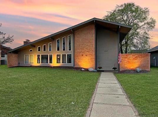 This architect-designed 1961 mid-century modern sits directly across from park and splash pad. Within walking distance to  schools, church's, and businesses. Has been thoughtfully updated inside and out while keeping it original: dramatic vaulted ceilings with exposed beams, clerestory windows, brick accent walls and a great room that fills with natural light. The kitchen has a large center island with cooktop and seating for five, double wall ovens, stainless appliances, pendant lighting, and new flooring that carries through the main level. Two large walk-in pantries and main-floor laundry make this home extremely functional. The dining area opens to a brick fireplace and a four-season porch with brick floor, and a great room has a second fireplace and its own mini-split for zoned heat and A/C.The primary suite has vaulted beamed ceilings, a large walk-in closet, and a private bath. Two more bedrooms, a den, and a second four-season porch finished in cedar shake (currently a music/exercise room) round out the living space. Downstairs: a carpeted rec room with exposed-beam ceiling, a cedar sauna with adjoining shower, and plenty of storage.Outside, the 70x140 lot is professionally landscaped with paver walkways, a patio with a built-in outdoor kitchen and bar, a fire pit, mature shade trees, a fenced dog kennel, and an 8x20 shed. Two-car attached garage with tar drive.Recent updates: new roof, new flooring throughout the main level, two mini-split heat/AC units, new water heater.Move in ready, one of a kind gorgeous home.