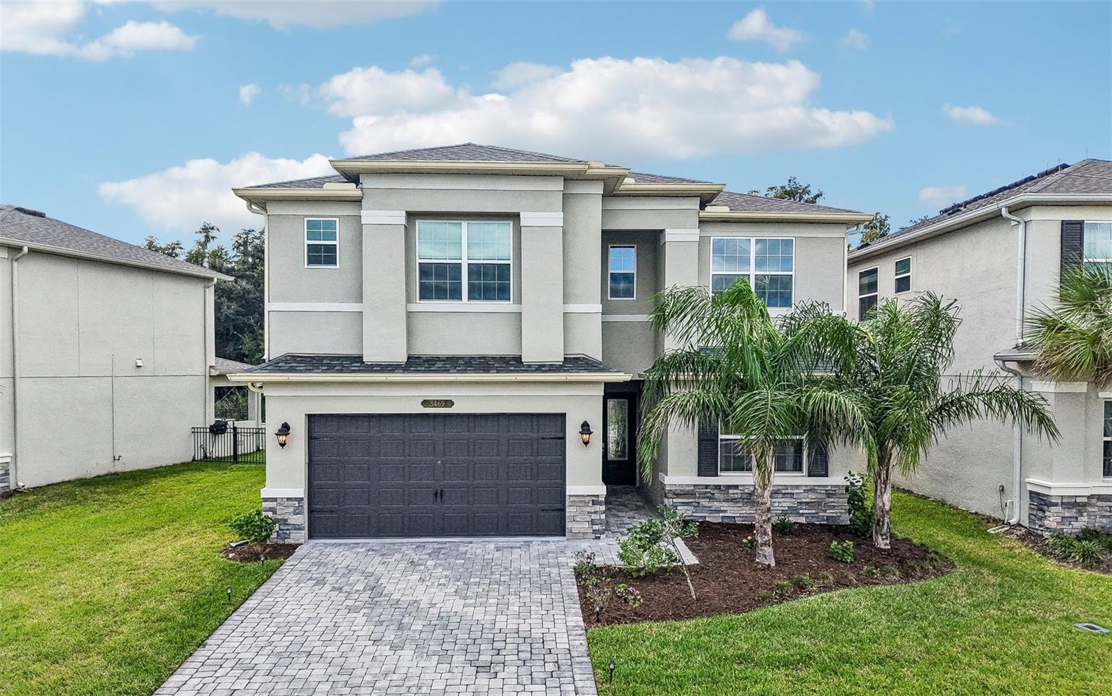 Virtually Staged. **LIKE-NEW LUXURY IN GATED WINDING RIDGE!** Built in 2023 and beautifully positioned on a private conservation lot, this impressive 5-bedroom, 4.5-bath residence offers the perfect blend of modern design, elegant finishes, and versatile living space in Wesley Chapel. A striking stacked-stone facade, pavered driveway, and leaded-glass entry door with sidelight create a welcoming first impression, while the light-filled interior showcases a neutral color palette, upgraded lighting, and an open floor plan designed for both everyday living and entertaining.The heart of the home is a beautifully appointed kitchen featuring light 42-inch cabinetry with crown molding, under-cabinet lighting, elegant gold hardware, and a spacious island with breakfast bar and pendant lighting. Upgraded appliances, including a gas range with a statement range hood, add both style and function. The kitchen flows seamlessly into the expansive family room, where triple sliding glass doors invite natural light inside and open to the pavered lanai overlooking the peaceful conservation setting. Decorative molding and wall sconces add refined character throughout the main living areas, while a private office with built-in cabinetry provides an ideal work-from-home space.A desirable main-level guest suite offers flexibility for visitors or multigenerational living. Upstairs, a spacious loft provides additional room for relaxing, entertaining, or creating a secondary living area. The generously sized primary suite serves as a private retreat, featuring dual walk-in closets and an en-suite bath with a garden tub, separate walk-in shower, dual sinks, and a dedicated vanity area. Additional bedrooms and bathrooms provide exceptional flexibility, while the included washer and dryer add everyday convenience.Beyond the home, gated Winding Ridge offers an outstanding collection of community amenities, including a resort-style pool, clubhouse, fitness center, playground, sports courts, and more. With its newer construction, versatile five-bedroom layout, sophisticated finishes, and tranquil conservation backdrop, this move-in-ready home presents an exceptional opportunity to enjoy modern living in one of Wesley Chapel's desirable gated communities.