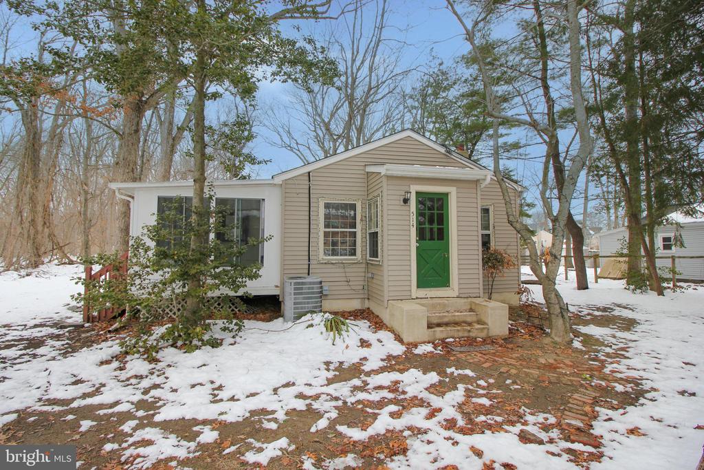 Own this charming cottage nestled in nature among mature trees! The open floor plan creates a spacious feel, with the living and dining areas flowing seamlessly into the kitchen. Natural stained wood trim throughout adds warmth and character, while large windows fill the home with sunlight and showcase views of the towering trees surrounding the property.The island kitchen features a skylight, tile countertops, and a full appliance package. The nicely sized sunroom offers a peaceful space overlooking the large wooded backyard—perfect for relaxing and enjoying nature. A convenient half bath off the kitchen is ideal for guests.The bedrooms share a full bath with a tub/shower combination. With a little TLC and cosmetic updates, this home offers wonderful potential as a cozy starter home or a tranquil retirement retreat.