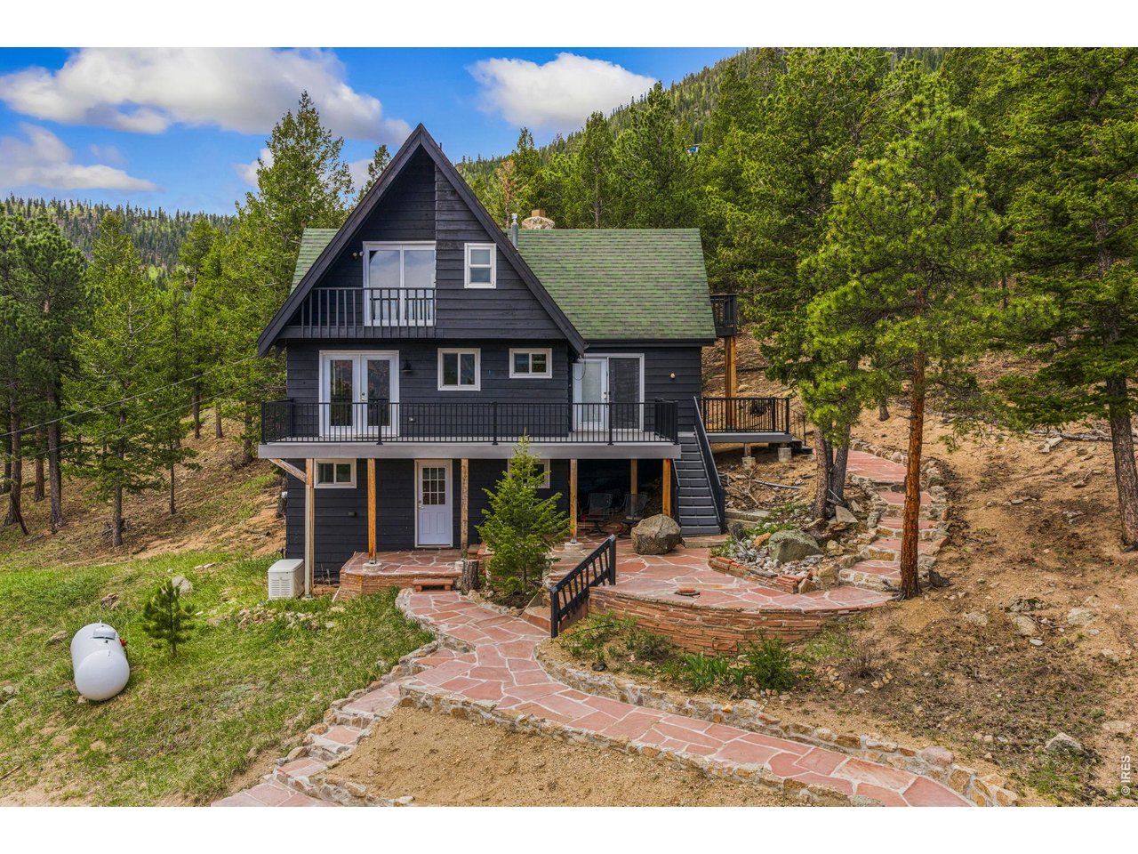 Welcome to your private mountain retreat, where peaceful living meets thoughtful updates and natural beauty. Nestled on 1.7 serene acres, this charming 2-bedroom, 1.5-bath home features an open layout with vaulted ceilings, creating a bright, airy feel throughout. Enjoy a nicely updated interior designed for comfort and functionality, complemented by large windows that capture stunning mountain views. Step outside to beautifully crafted flagstone walkways, surrounded by mature trees. Take in the abundance of local wildlife from your expansive deck, perfect for those seeking tranquility and a connection to nature. This property is equipped with a whole-house generator for added peace of mind and a single-car carport for convenience. A standout feature is the large detached building with electricity, skylights, and a small office area. offering endless possibilities-whether you need a workshop, studio, storage space, or potential guest quarters. Private, peaceful, and full of character, this unique property is the ideal escape while still offering practical amenities for everyday living. Wonderful opportunity to make it your own special slice of mountain living.