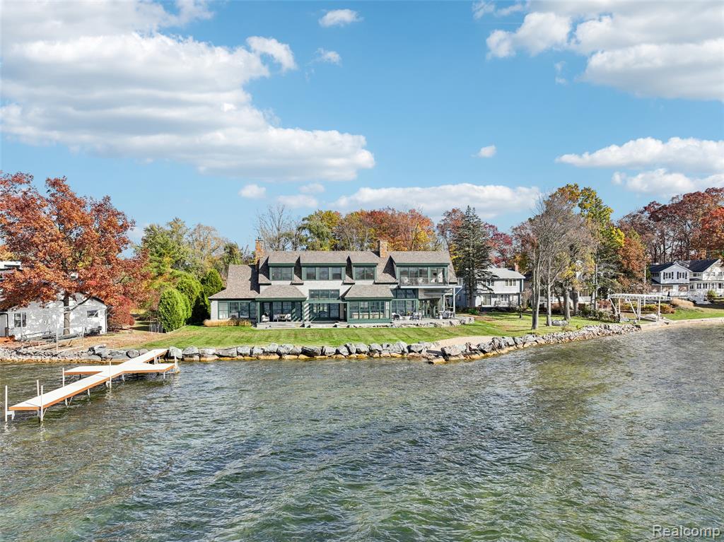 Nestled along the shores of 850 acre all-sports Lake Fenton, this exceptional lakefront residence showcases 144 feet of prime frontage on nearly half an acre of private waterfront. Completely reimagined with meticulous attention to detail, the home blends warm, modern design with high-quality finishes—creating an elevated yet inviting lake lifestyle. Inside, expansive windows frame breathtaking water views and fill the home with natural light. A stunning custom stone fireplace anchors the living room, while the adjoining family room and sunroom provide relaxed gathering spaces with panoramic lake vistas. The gourmet kitchen is beautifully appointed with custom cabinetry and upscale finishes, seamlessly connecting to the outdoor living area—where a hard-packed sandy beach offers effortless access to the water just steps from your door. The main level features a private guest suite with a full bath, ideal for visitors or multigenerational living. Upstairs, the primary suite is a true retreat, highlighted by sweeping lake views, a thoughtfully designed custom closet, and a spa-inspired ensuite bath with luxurious details. Two additional bedrooms, a full bath, and a comfortable sitting area complete the upper level. An optional fifth bedroom or private guest suite above the garage, complete with its own bath, provides exceptional flexibility. Outdoors, western and southern exposures create the perfect backdrop for unforgettable sunsets. An oversized saltwater hot tub invites year-round relaxation, while the expansive yard offers both privacy and open water views. With heated tile floors on the main level, all-foam insulation for energy efficiency, and conveniently located laundry rooms on both floors, comfort and practicality are woven throughout. Sophisticated yet welcoming, refined yet relaxed—this is lake living at its finest on Lake Fenton.