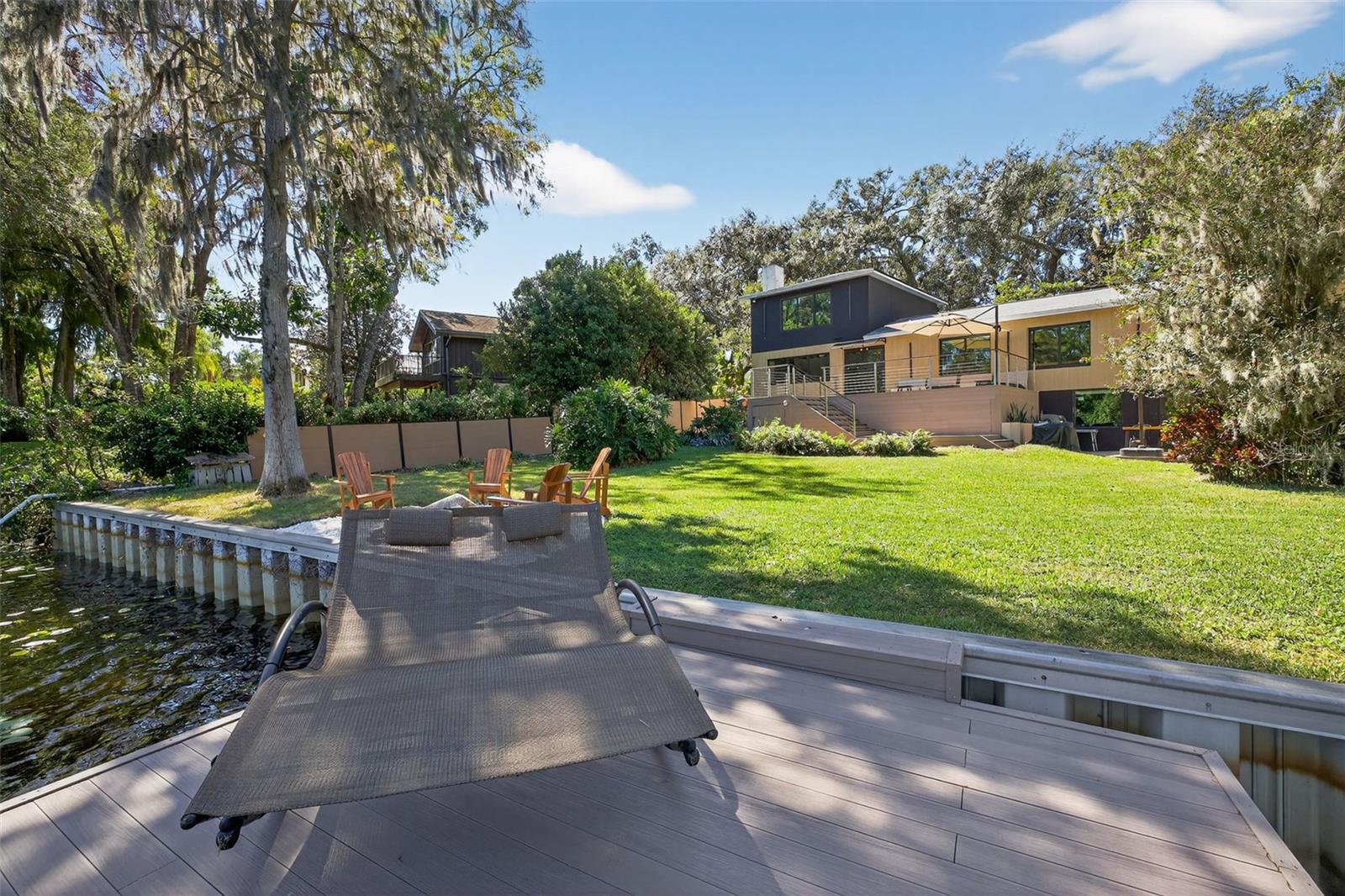Welcome to Riverhaus, a modern riverfront retreat designed for stillness and connection. Nestled beneath a canopy of oaks along the Hillsborough River, this architectural home blends clean lines, natural materials, and light-filled spaces to create a calm, restorative escape.  The house just finished a year long renovation, including new electrical, new flooring, new  Hurricane impact windows, New Kitchen, 2 more new bathrooms were added and all remodeled, Replaced Terrace.The house offers:- Direct riverfront with private dock and firepit lounge- 5 bedrooms • 4 baths • sleeps up to 14 guests- Chef’s kitchen, dining terrace, and outdoor kitchenThe SpaceEvery inch of Riverhaus feels intentional. Crafted for balance between modern design and organic warmth. Large steel windows frame river views, while layered wood and stone textures soften the architecture.Living & Dining- Open-concept living area with sectional seating and Smart TV- Statement stone fireplace as the room’s focal point- Dining area for 12 with river views through floor-to-ceiling glass