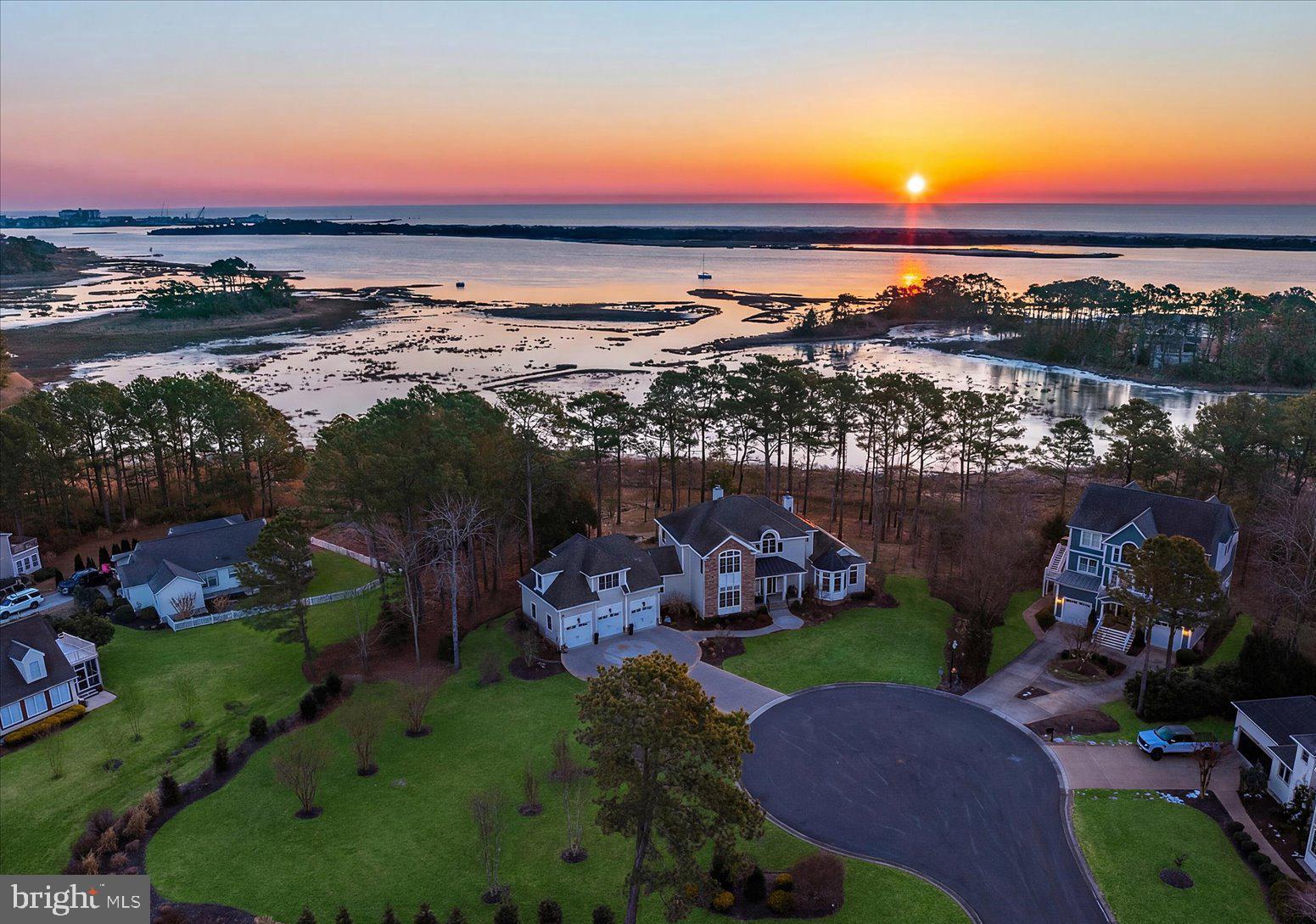 Newly repositioned pricing, 9515 Harbor Lights Dr. in West Ocean City, Maryland presents a compelling opportunity to experience elevated coastal living in the Ocean Reef community. This masterfully designed custom-built waterfront residence sits on over 1.39 acres at the end of a private cul-de-sac, creating a secluded coastal retreat with exceptional privacy and sweeping panoramic views of the bay, the unspoiled natural beauty of Assateague Island—renowned for its protected shoreline, wild horses, and untouched coastal landscape—the Ocean City Inlet, and the iconic skyline of the world-famous Boardwalk, complete with the Ferris wheel and roller coaster along Maryland’s coastline. From the moment you step inside, the intention of architectural design is immediately felt. A custom front door featuring circular glass detailing sets the tone, with this signature motif thoughtfully repeated in complementary architectural elements throughout the home. An elegant foyer with designer lighting opens to a dramatic great room where walls of glass flood the space with natural light and frame sweeping water views. The kitchen is a true chef’s kitchen designed for culinary performance, anchored by an oversized island, professional-grade appliances, custom cabinetry, and bayfront dining designed for both elevated entertaining and everyday enjoyment. The open-concept layout ensures seamless flow between living, dining, and gathering spaces, all oriented to maximize the home’s breathtaking waterfront setting. This custom coastal residence offers 5 bedrooms, 3 full bathrooms, and 1 guest bathroom, along with a den/office/media room that could function as a 6th bedroom, thoughtfully designed to balance luxury and livability. The owner’s suite is a private sanctuary, generously scaled and appointed with a sitting area, wet bar, and gas fireplace set into a striking statement wall. A private balcony captures expansive bay views, while the spa-level bath and walk-in closets complete the retreat-like experience. A separate staircase leads to a beautifully appointed guest suite intentionally designed to provide privacy and autonomy for extended stays, featuring a combined living room and office space, sauna, bayfront bedroom, and en suite accommodations that create the comfort and functionality of a private residence within the home. Outdoor living is elevated to a resort-style experience with multiple levels of maintenance-free Trex decking creating distinct dining and lounge areas, complemented by a built-in grill and bar island with flexible seating, fire pit lounge, and tranquil fountain—perfect for entertaining against the backdrop of the bay. Completing the property is a collector’s three-car garage with finished flooring and a built-in workstation offering both functionality and refinement. Additional features include a private elevator servicing multiple levels and a built-in fire sprinkler system for added safety and peace of mind. An integrated Control4 smart home system further enhances modern living, offering seamless control of lighting, climate, security, and home audio-visual systems with customizable automation designed for comfort, efficiency, and effortless coastal entertaining. Every element of this home reflects intentional architectural design, curated craftsmanship, and a commitment to coastal luxury living at its highest level.