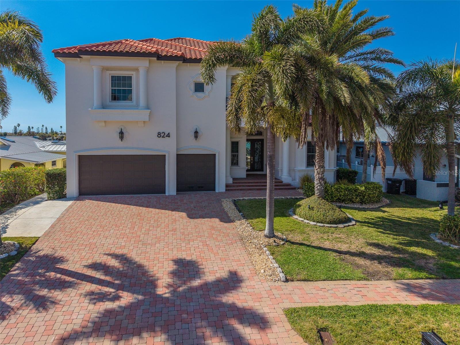Your waterfront dream home awaits at 824 Island Way. Perfectly positioned on the open water side of Island Estates, this nearly 5,000-square-foot custom-built Mark Maconi residence delivers luxury coastal living with two spacious primary suites and an exceptional list of recent upgrades.The home now showcases a freshly painted exterior with a refined Mediterranean flair, complemented by new exterior lighting that enhances its architectural detail and evening curb appeal. Additional improvements include a stunning tile roof, solar panel system, two 16-foot sliding glass door systems, and two extended composite decks that expand your outdoor living space and maximize the stunning waterfront views. A floating dock was also added in 2021.Step through the grand foyer and take in sweeping views across the Mandalay Channel toward the Gulf of America. Custom plantation shutters add elegance throughout, while the main-floor study features built-in shelving and can easily serve as a sixth bedroom. A well-appointed butler’s bar with a built-in wine refrigerator sits conveniently near the private elevator. The chef’s kitchen is designed for entertaining and everyday ease, offering a large island, Viking gas range, stainless steel appliances, built-in oven and microwave, and a central vacuum system.Upstairs, a thoughtful split floor plan provides privacy for two impressive primary suites. The main suite features an oversized bath with a walk-in shower, separate floating tub, built-in shelving, dual vanities leading to one private water closet on the right with a washer/dryer closet on the left, and a generous walk-in closet. Private east- and west-facing balconies offer breathtaking sunrise and sunset views. The secondary suite includes a wet bar, two closets, a full bath with double vanities and walk-in shower, plus a private office that opens to its own balcony. Three additional bedrooms, two bathrooms, an oversized laundry room, and abundant storage complete the second level.Outdoor entertaining is effortless with a heated saltwater pool with full automation controlled via smartphone app, outdoor kitchen and grill.  The refurbished dock features a 16,000-pound lift and a deep-water slip accommodating vessels up to 70 feet.The three-car garage houses the tankless water heater system, Air Vac filtration system, and the complete Enphase solar battery backup system. Elevated above many neighboring homes with a 12 foot elevation, this property benefits from reduced flood insurance costs and added peace of mind with its solar power system—essentially functioning as a built-in generator.Located in the coastal Island Estates community, home to Clearwater Marine Aquarium, residents enjoy close proximity to Island Way Grill, Publix, and the world-famous shores of Clearwater Beach.Discover your private waterfront sanctuary at 824 Island Way—where dolphins play just beyond your dock and spectacular Gulf Coast sunsets are part of your everyday view.