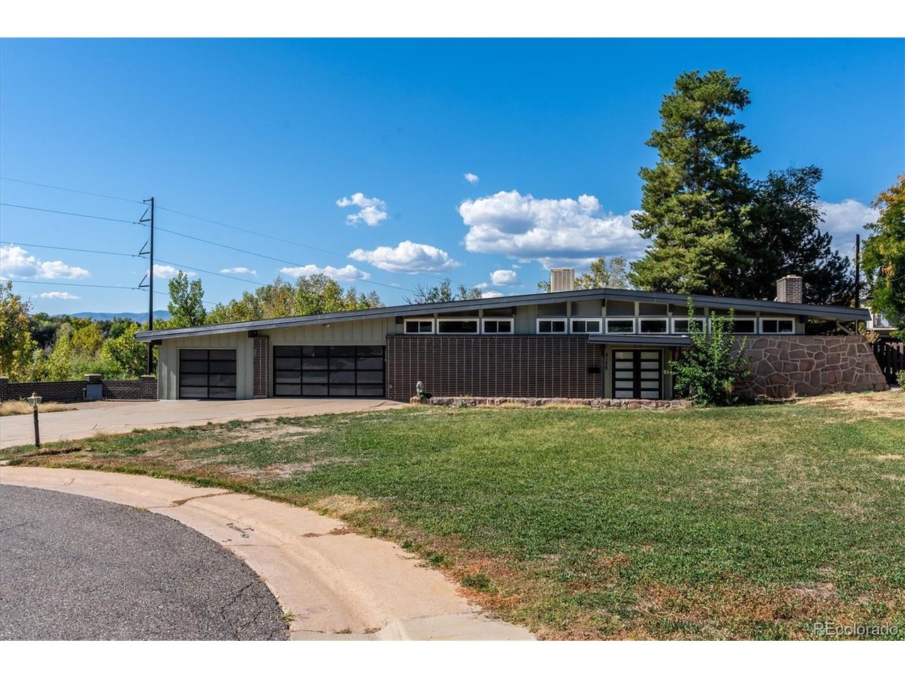 Mid Century Modern Marvel...Located at the end of a private cul-de-sac bordering Big Dry Creek on almost a one-half-acre lot.  Light and bright throughout, with expansive windows that flood the home with natural light on both levels. Enter through the modern front door and into a welcoming foyer and walk up into the upper level on a floating open risered wood staircase with modern railing and into the wide open space with instant access to the dining room, living room with a full stone wall highlighted by a wood burning fireplace with access to the enclosed in bonus room. Open kitchen with new soft closing cabinets, slab quartz countertops, subway tiled back splash and brand new high end stainless steel appliances. Just off the kitchen is a eat in nook area with sliding door access to the oversized deck and covered conditioned living space area with "modern garage door" access.  New hardwood floors throughout the upper level and highlighted with original T&G ceilings and beams.  The lower level has a warming feel as you enter an oversized family room with LVP flooring and wood burning fireplace with a brick surround. Three large bedrooms with garden level windows, full bathroom and another enclosed condtioned flex room area with walk-out access to the large back yard with one of a kind brick fence with mature landscpaing. Double pane windows, evaporative cooler, brand new designer exterior paint.  Original natural stone and brick exterior facade.  3 car attached garage with high end modern glass garage doors and openers.  The third bay garage has its own enclosed walls, lighting and two small industrial roll up doors with a private patio overlooking the creek below and the mountains.  Additionally, it has a West facing garage door that can be opend into the back yard.  This is a perfect home for a family or for those who love to entertain.  Easy access to trails, parks, schools, restaurants, bars, Old Littleton, Southglenn and all major highways and throughfares!