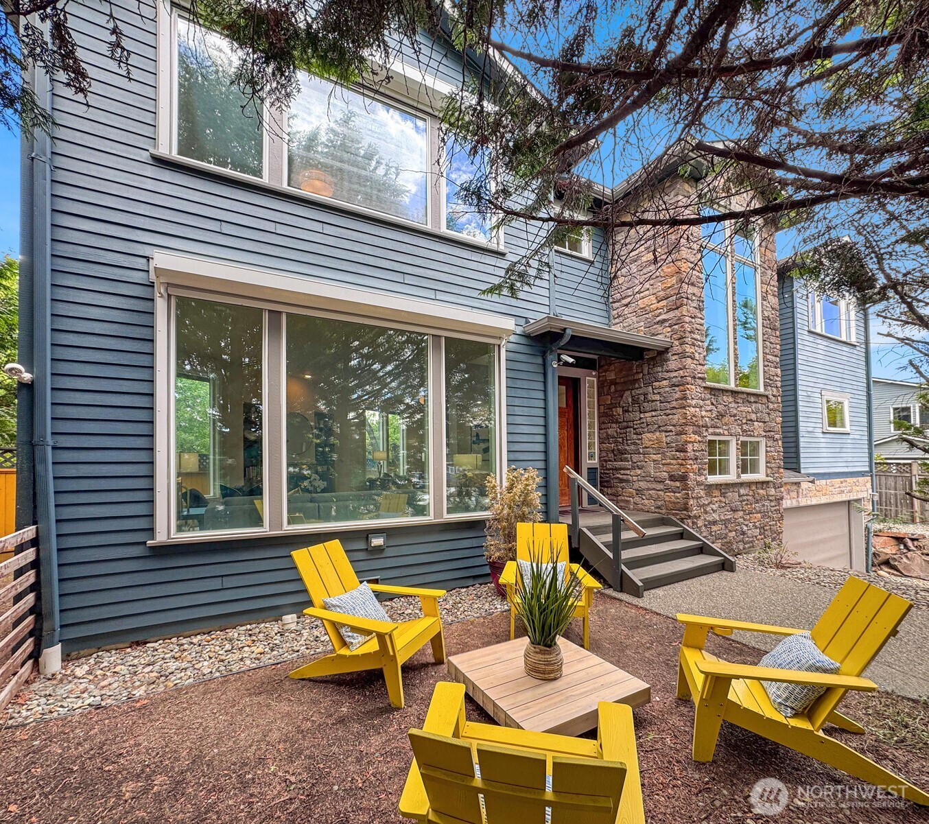 Exceptional home highlighting modern Pacific Northwest design on corner lot in vibrant Wallingford. Bright, open interiors are designed for entertaining, featuring a dramatic sunken living room with fireplace, expansive windows, and seamless flow between gathering spaces. Stylish kitchen offers sleek quartz counters, stainless appliances, and pantry storage. French doors open to fenced patio and yard for effortless indoor-outdoor living. Spacious primary suite includes spa-inspired bath with jetted tub, separate shower, dual vanity, and walk-in closet. Enjoy views of the downtown skyline and Mt. Rainier from upper level. Attached 2-car garage, and quick access to Fremont, Green Lake, Woodland Park, restaurants, cafés, transit, and major commuter routes.