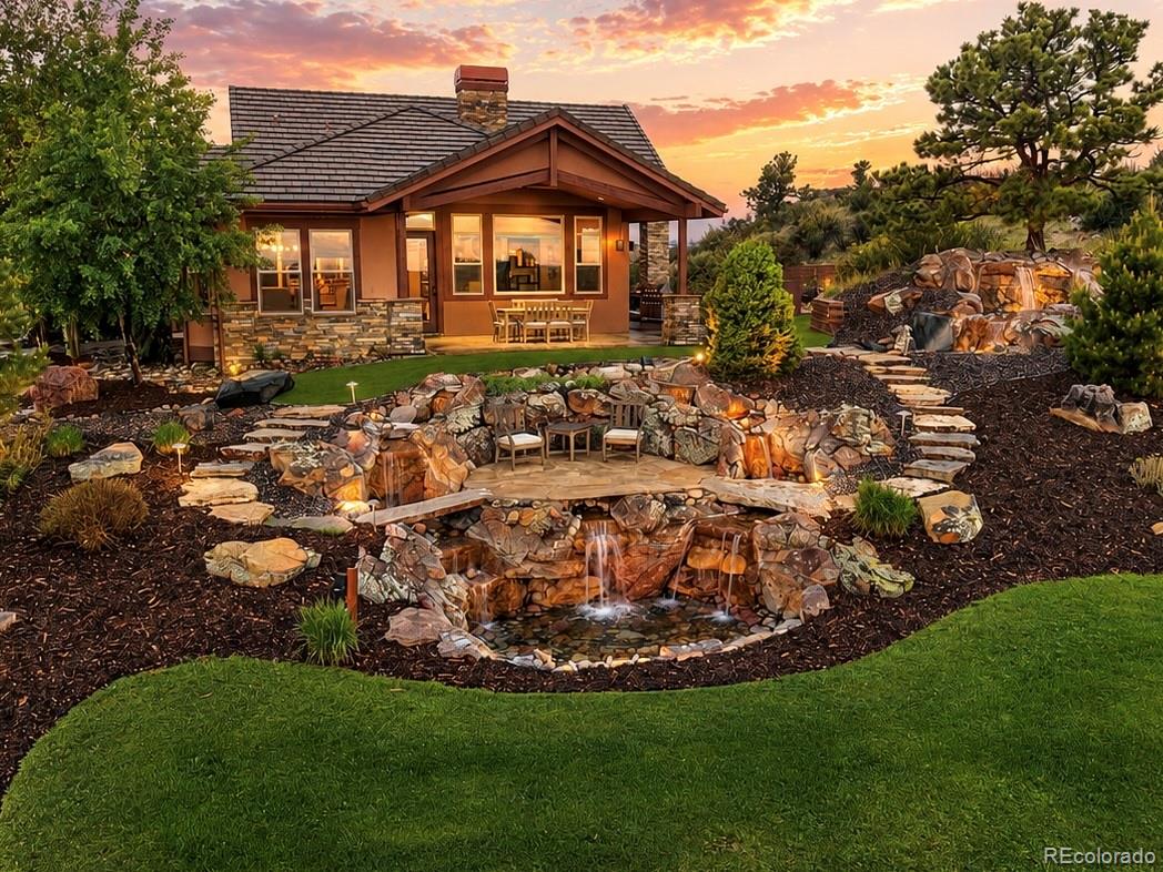 Nestled high on the hill in the prestigious Pradera golf community, this extraordinary ranch-style estate offers unmatched privacy, breathtaking panoramic views, & an incredible setting just off the 14th green of The Club at Pradera. Situated on one of the largest lots in the neighborhood, this home is a rare blend of luxury, comfort, & resort-style outdoor living. The beautiful main level showcases high-end finishes throughout, including a completely reimagined gourmet kitchen with luxury appliances and an exquisite primary suite remodel designed to rival a five-star retreat. A stunning two-sided fireplace creates warmth and ambiance between the elegant den and expansive open-concept great room, where the kitchen, dining, and living spaces seamlessly connect for everyday living & entertaining. Walls of windows and direct access to the covered patio perfectly frame golf course & Colorado views. Multiple outdoor living spaces offer unique experiences throughout the property, from private seating areas and pristine turf gathering spaces to native grassland fire pit retreats & a spectacular waterfall feature creating a resort-like atmosphere. Automotive enthusiasts and hobbyists alike will appreciate the seven-car garage configuration, complete with an extended circular driveway and separate access to an additional attached garage space ideal for guest quarters, multigenerational living, a studio, or collector’s retreat. The main level features two bedrooms, including the luxurious primary suite, while the expansive walkout basement offers two additional bedrooms, multiple full bathrooms, a recreation room, theater room, & versatile flex space ideal for a gym, office, or wellness studio. One lower-level bathroom features a steam shower, adding to the home’s spa-inspired feel. This is more than a home — it is one of Pradera’s true showcase properties, with exceptional privacy, & unforgettable indoor-outdoor living in one of Parker’s most coveted golf course communities.