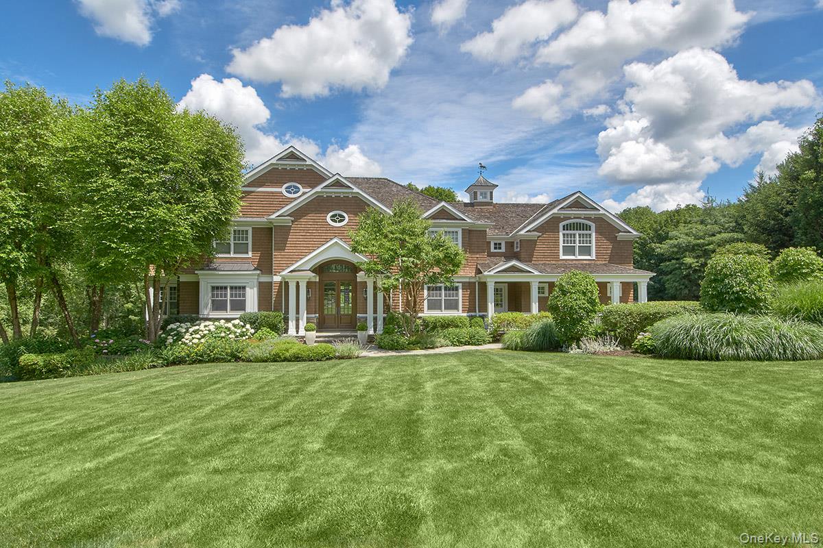 Nestled on over 5 private, professionally landscaped acres in the exclusive cul-de-sac of Sutton Farm within Chappaqua’s esteemed Whippoorwill area, this custom-designed and custom-built Shingle Style home is a rare and refined first opportunity. Completed in 2008 by a renowned builder and architect, the 4+ bedroom home (lives like a 5/6) has been meticulously detailed with luxurious, high-end finishes that elevate every detail. A gracious covered front entry welcomes you to a dramatic two-story foyer with soaring ceilings, a sweeping curved staircase, and exquisite architectural detailing throughout. The shingle and stone facade exudes timeless curb appeal, while inside, craftsmanship and quality reign supreme. The thoughtfully designed open layout showcases wide-plank white oak floors and designer light fixtures from Holly Hunt, Visual Comfort, Jonathan Adler, and Boyd, imbuing each space with modern sophistication. At the heart of the home is a professionally appointed chef’s kitchen. A dual oven 6-burner range with grill by Wolf is accented by a custom-designed stainless steel hood. Built-in Subzero refrigeration features dual 36’ refrigerator freezers. Quartz and marble countertops, two dishwashers, and two sinks complete this exquisite space. Ideal for both entertaining and everyday living, the inviting breakfast area flows seamlessly into the sun-drenched family room with a custom masonry stone fireplace. The main level also includes a formal dining room with butler’s pantry, a gracious living room with a second masonry fireplace, a sunlit private office, and a well-equipped mudroom with back staircase. The second level includes a separate guest suite/bonus room and additional office space—ideal for multigenerational living or working from home. The luxurious primary suite offers a peaceful retreat with a tray ceiling, a dressing area, generous walk-in closets, and a spa-like bath. Three additional spacious bedrooms each feature en-suite baths. The finished walk-out lower level adds remarkable versatility with a large recreation room, game room, gym, full bath, guest/office suite, and abundant storage.The exterior grounds are truly an outdoor oasis: sweeping lawns, specimen trees, perennial gardens, and complete privacy. A newly paved Belgian block-lined driveway provides a grand entrance, while the expansive backyard features an oversized deck, perfect for entertaining, recreation, or serene relaxation. Additional highlights include a three-car, double-height garage, radiant heat, and whole-house generator—offering ultimate comfort, efficiency, and peace of mind. Located on once historic Sutton Farm, this one-of-a-kind home offers the best of both worlds: seclusion and serenity just minutes from Chappaqua, Armonk, schools, and train. Nature preserves are nearby for peaceful hikes. A rare and refined opportunity—perfection in every detail.
