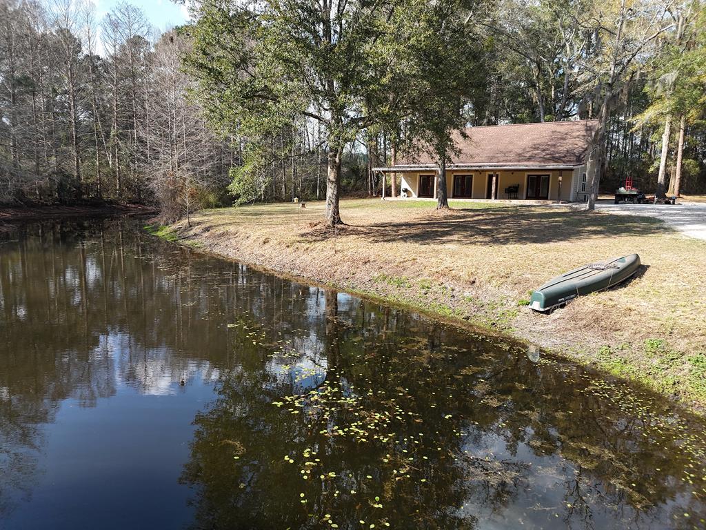 Step into your own private frontier at 415 Jane's Lane in Ochlocknee GA! This rustic 3BR/2Bath home sits on 12 sprawling acres, features a meandering gated driveway, and has all the fish you can catch in your own private pond, right outside the front door. Inside you will find huge open living space, all accented by gorgeous knotty pine interiors and exposed brick. The living room flows nicely into a well-appointed kitchen equipped with the latest appliances, and nice dining area. Big French doors offer amazing views of the property, and lead right out onto the wonderful front porch. Home was built in 2009 beyond traditional construction code to withstand severe storms. Recent additions include new flooring, new carpet in bedrooms, new kitchen cabinets including the island, new countertops, new flagstone on the front porch and new metal roofing over the porch. The primary suite is massive, and features its own bathroom and walk-in closet. Two other bedrooms at the back of the house share another full bath. Aside from the shady and scenic pond, the property also features beautiful stands of pine and oak trees, and 8 acres recently planted in pecan trees and irrigated. Pecan varieties include Oconee and Avalon, which is a fairly recent variety developed by the University of Georgia, and Elliot varieties for pollination. All this in a great private community along Jane's Lane. Call your favorite agent TODAY for a closer look at this amazing property. Click here for a virtual tour: https://my.matterport.com/show/?m=nVZCgH7yN3E&mls=1