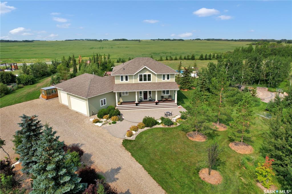 Welcome the perfect Saskatchewan paradise — an extraordinary 2-storey Westridge built home set on just over 5 beautifully landscaped acres, only 12 minutes from Saskatoon. This property offers the perfect blend of luxury, space, and outdoor lifestyle, with every detail thoughtfully designed for comfort and style. You'll be welcomed by the gorgeous East facing porch perfect for a morning coffee. Step through the grand front entrance into a bright, open interior filled with natural light. The open floor concept allows for the perfect family or entertaining setting. The kitchen's oversized island and gorgeous quartz countertop with a corner pantry make it the perfect space to cook and connect. The main floor features an office, large mudroom with laundry and a stunning primary bedroom retreat, complete with a spa-like ensuite and a spacious walk-in closet. Upstairs, you'll find three more bedrooms plus a large bonus room, offering plenty of space for family, guests and everything in between. Outside, the exquisite yard is an entertainer's paradise. Enjoy summer evenings with your very own outdoor kitchen, wood-fired pizza oven, and above-ground pool, all set against the backdrop of breathtaking Saskatchewan sunsets. A heated triple attached garage provides ample space for vehicles, toys, and tools, making this property as functional as it is beautiful.